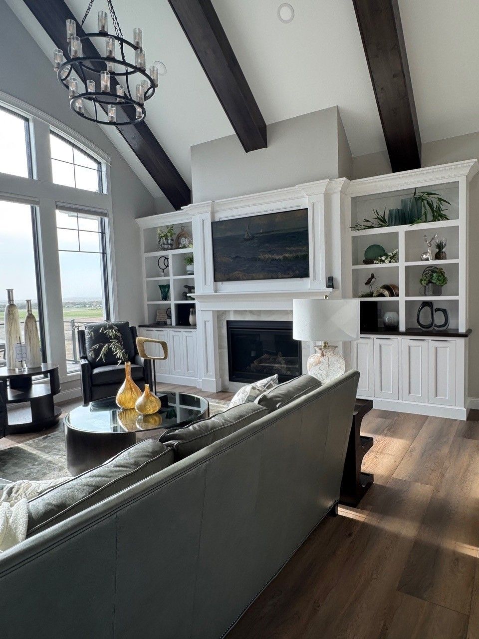 Bright living room with vaulted ceiling, fireplace, built-in shelves, and large windows overlooking water.