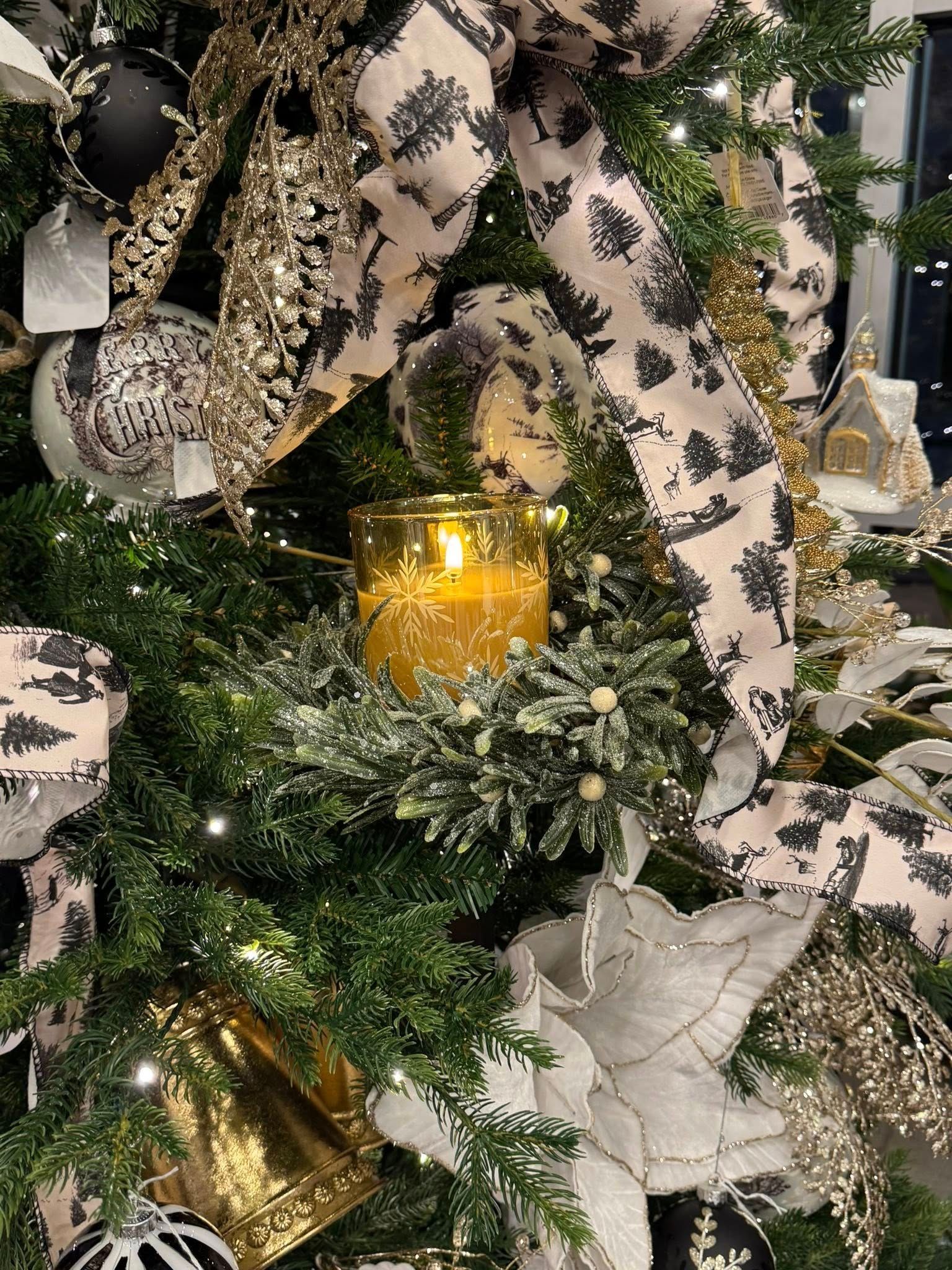 Holiday wreath with gold candle, black-and-white ribbon, and frosted greenery