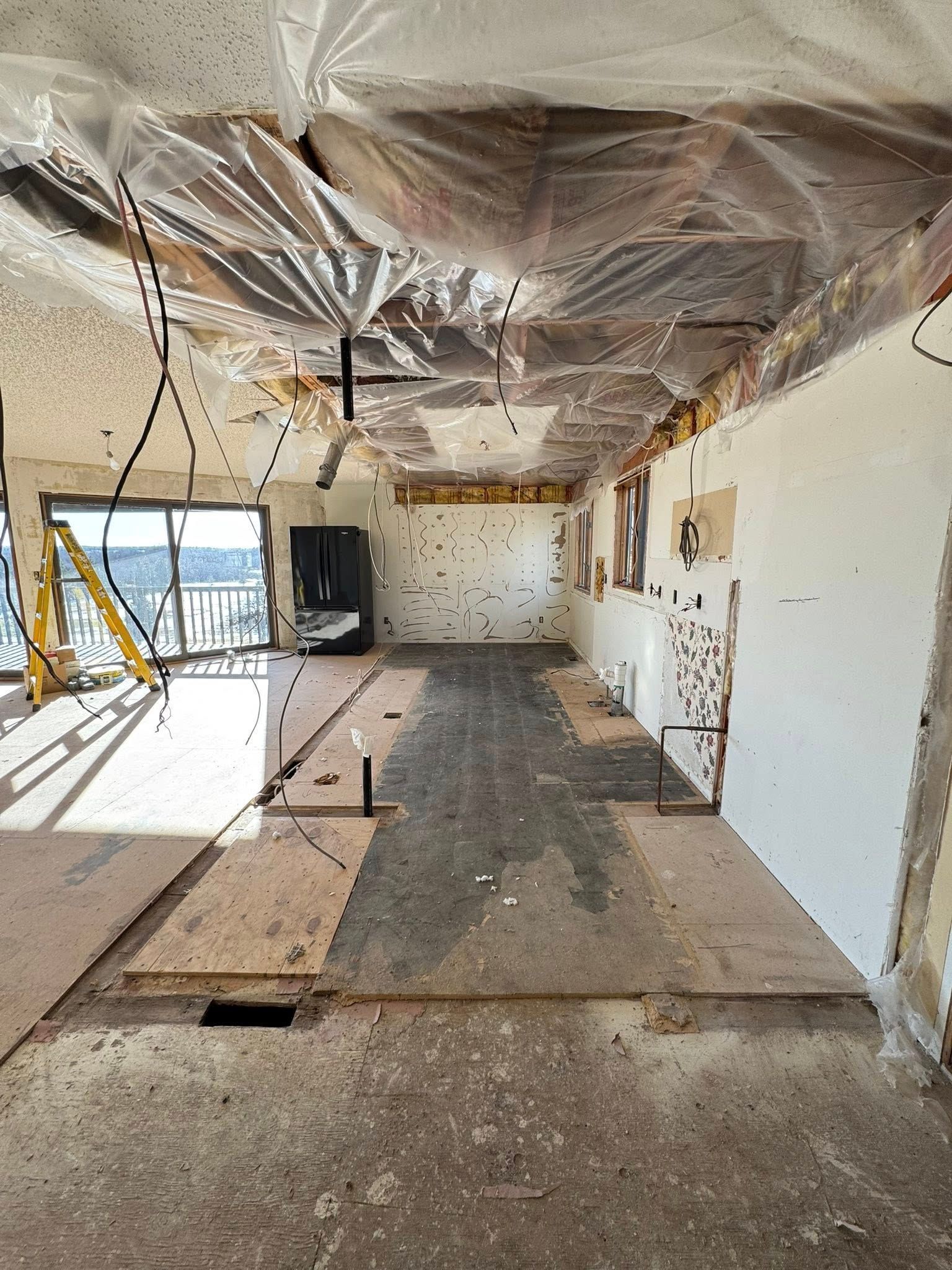 Partially demolished room with exposed ceiling, debris, and boards on the floor during renovation