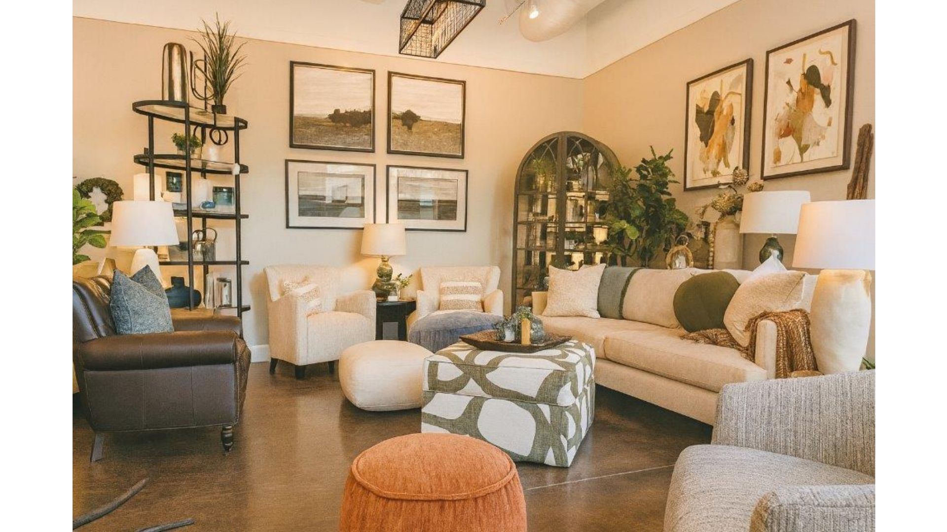 Cozy living room with beige sofa, white chairs, framed art, mirror, plants, and warm neutral decor.