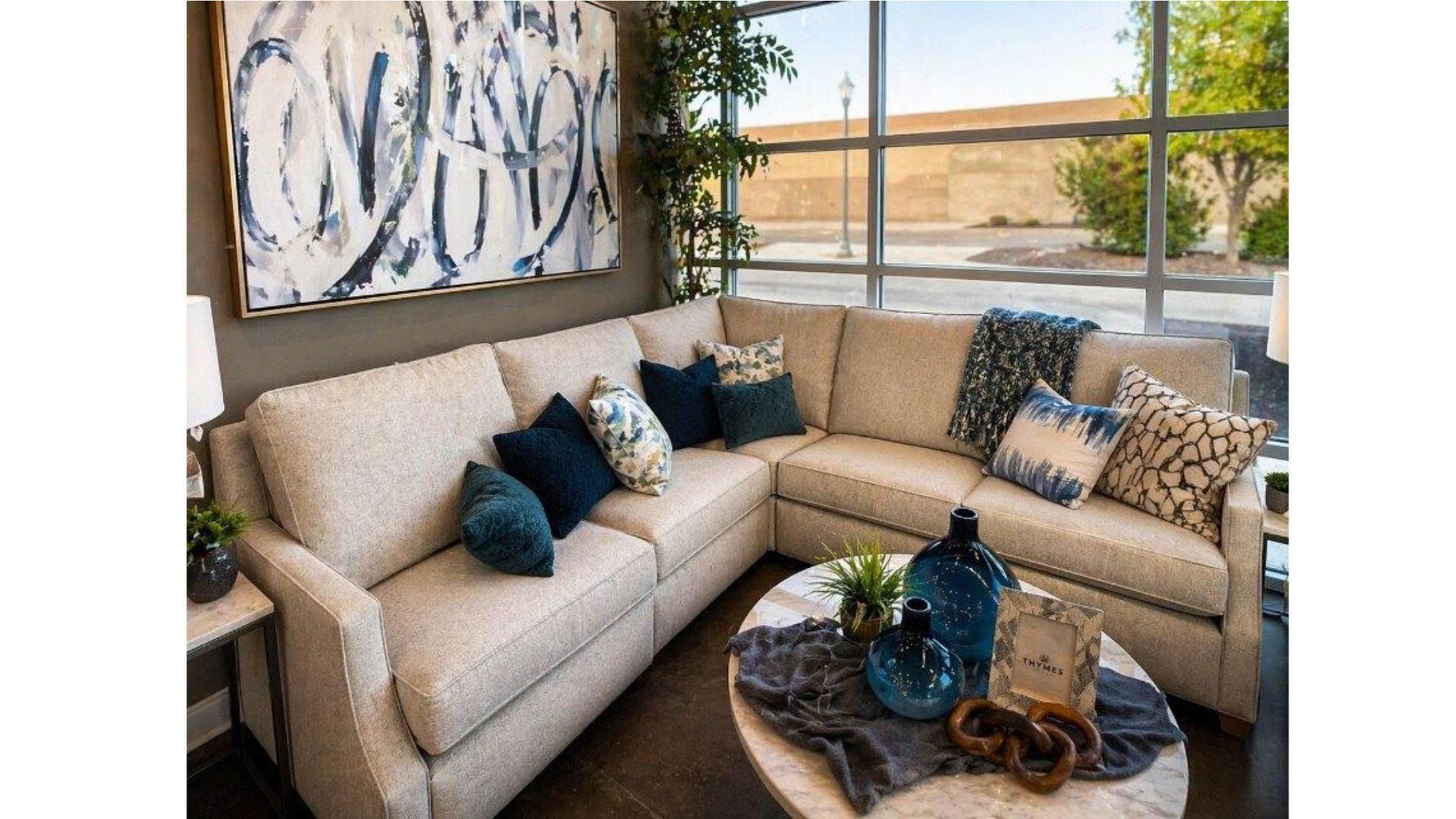 Cozy beige sectional in a bright living room with abstract wall art and a round coffee table