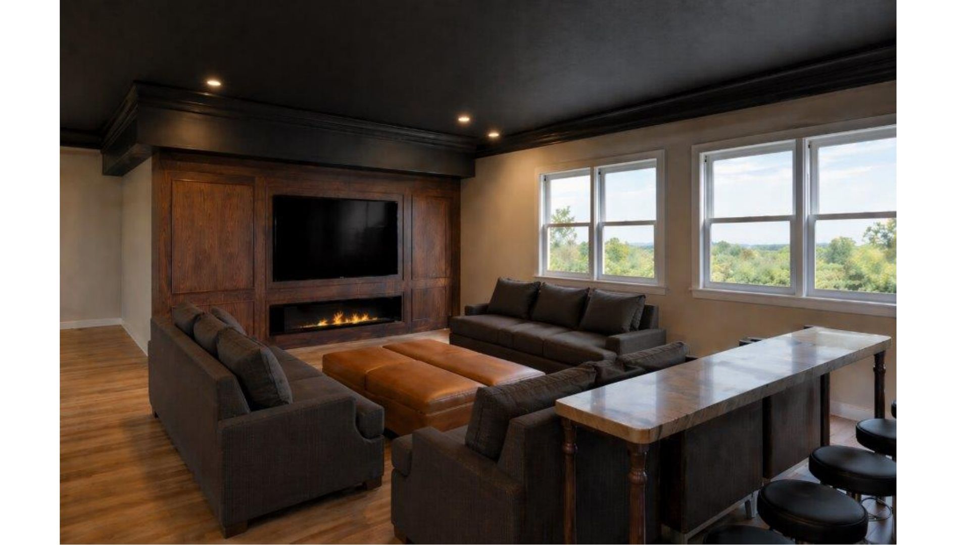 Modern living room with dark wood fireplace, gray sectional sofas, wooden table, and large windows