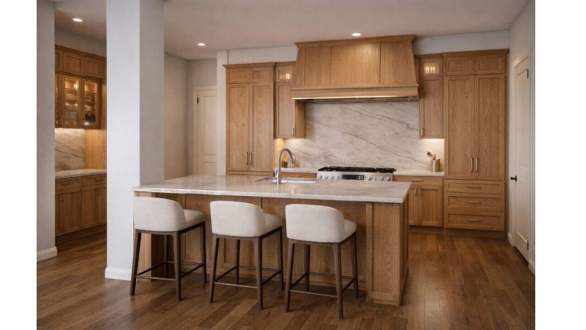 Modern kitchen with wood cabinetry, white island, and three stools under warm recessed lighting