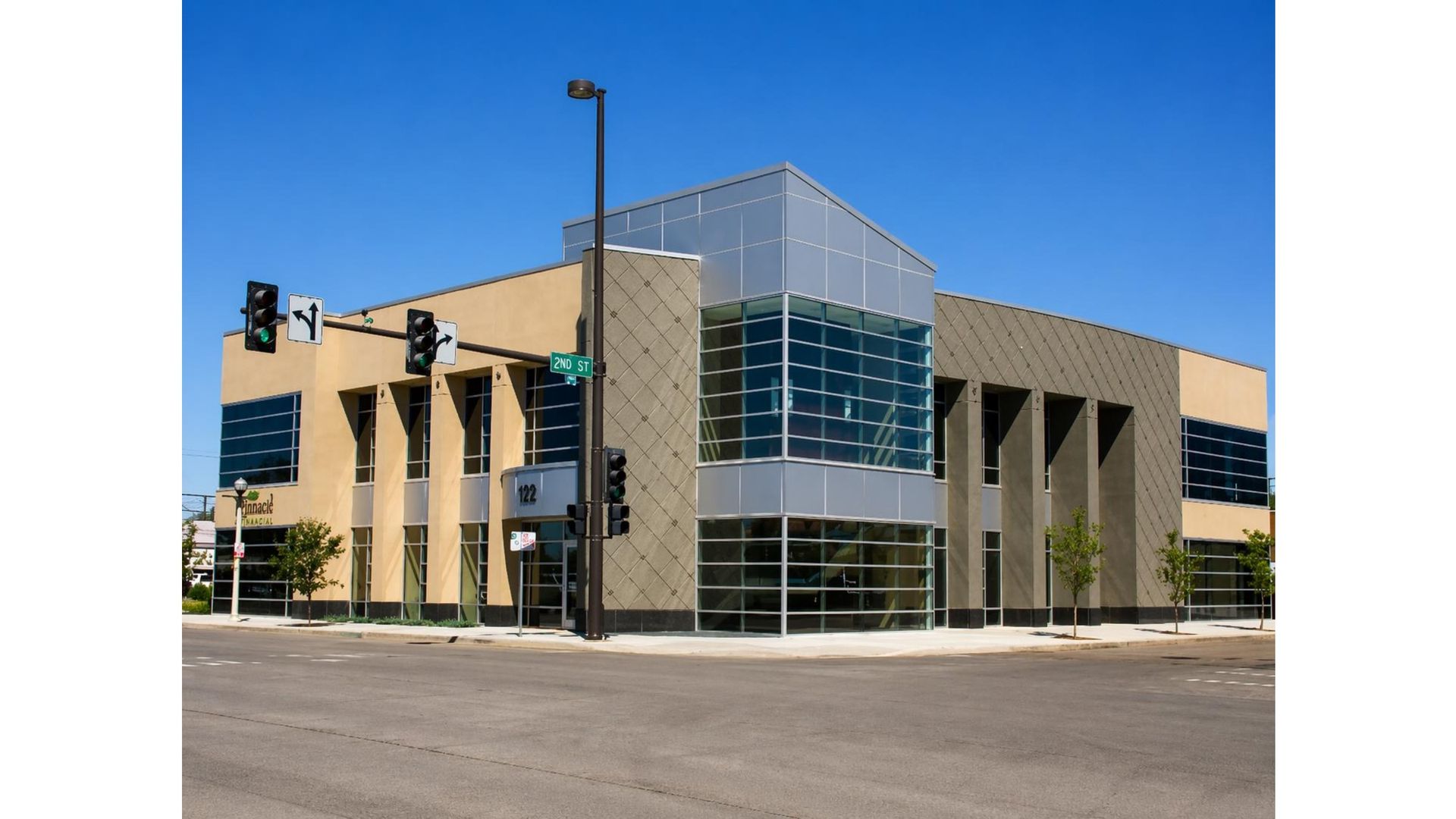 Modern glass-and-stone office building at a street corner under a clear blue sky