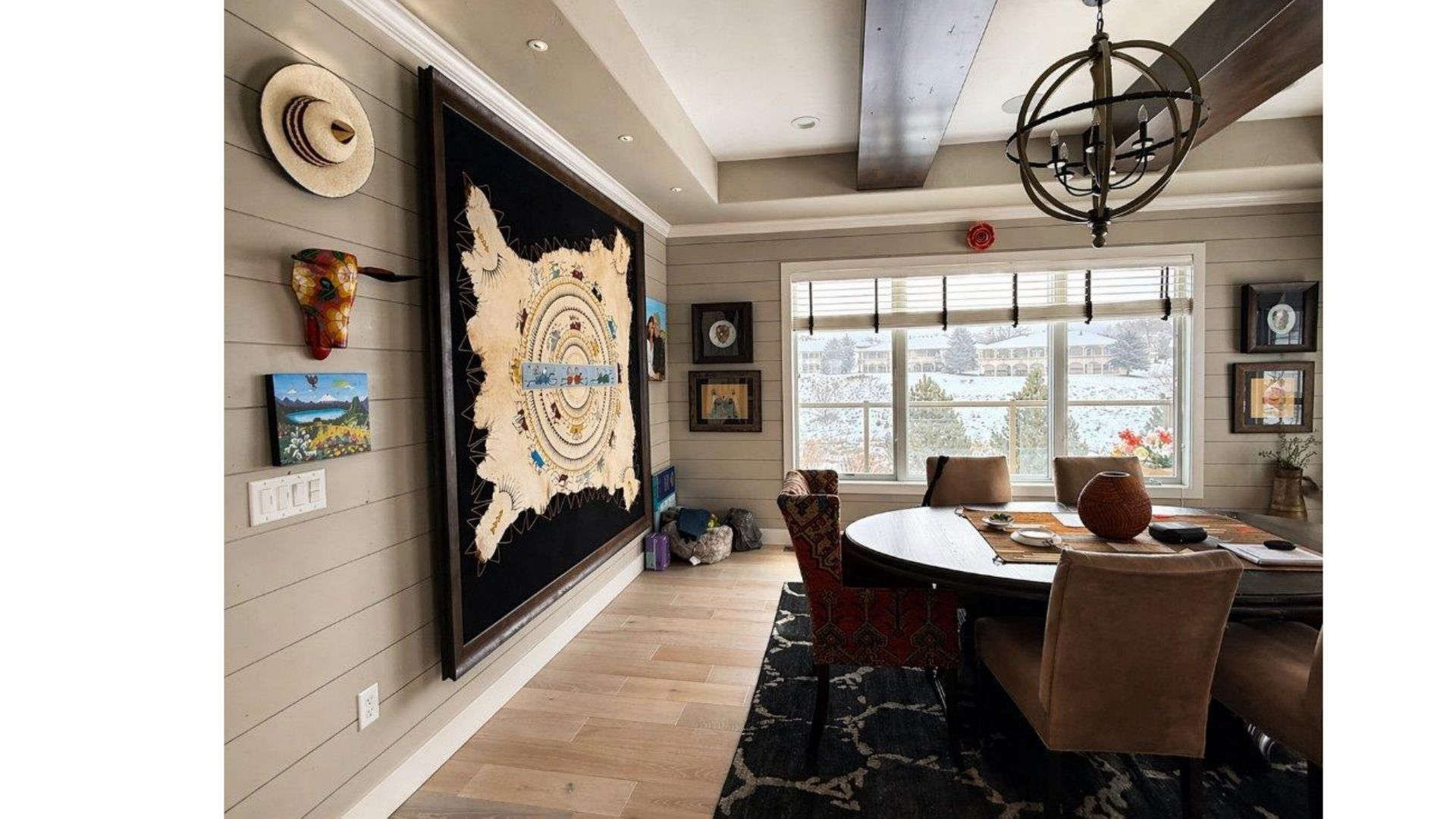Elegant dining room with large wall tapestry, chandelier, and table by bright windows