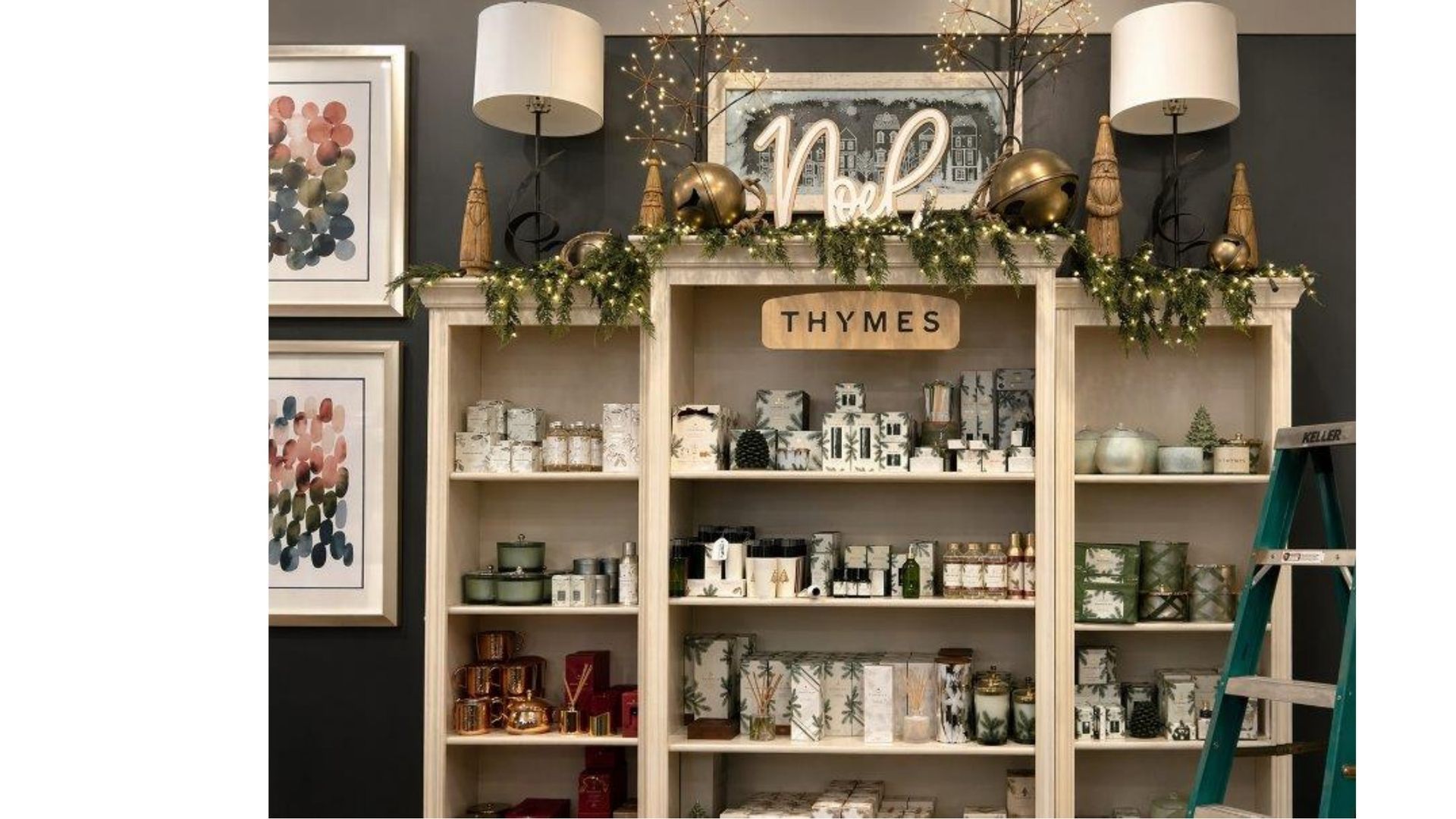 Decorated home shelves with candles, greenery, framed art, and a glowing “noel” sign above a mantle