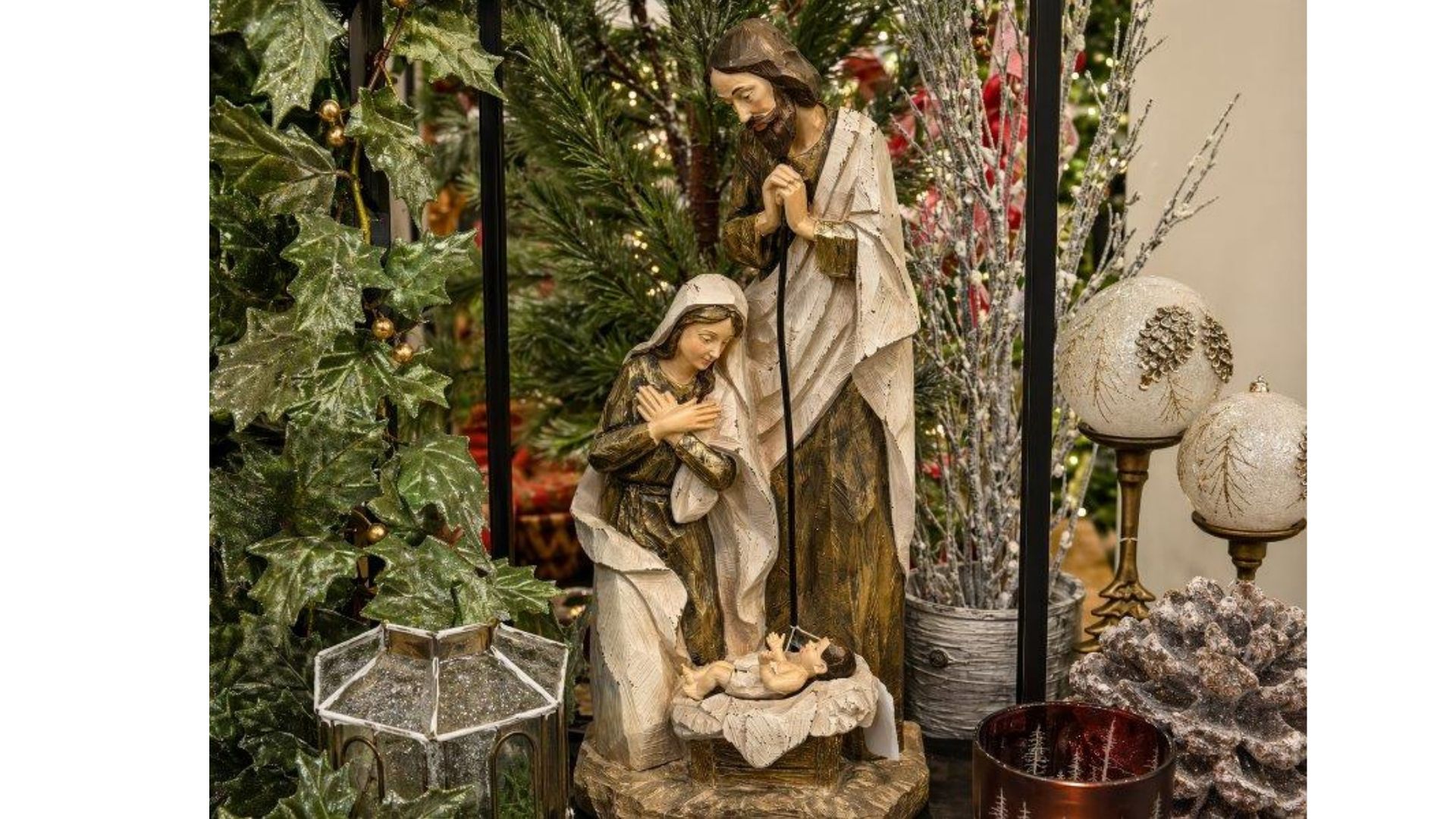 Nativity scene with Mary, Joseph, and baby Jesus surrounded by plants and decorative lights