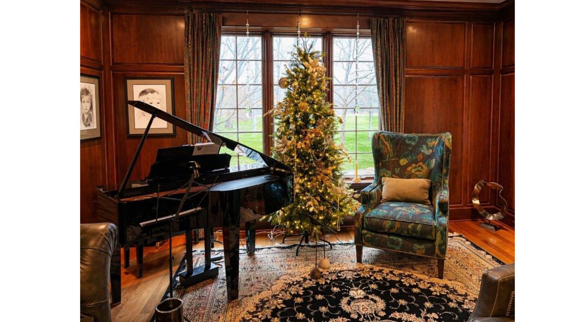 Grand piano and decorated Christmas tree in a wood-paneled room with an armchair and patterned rug