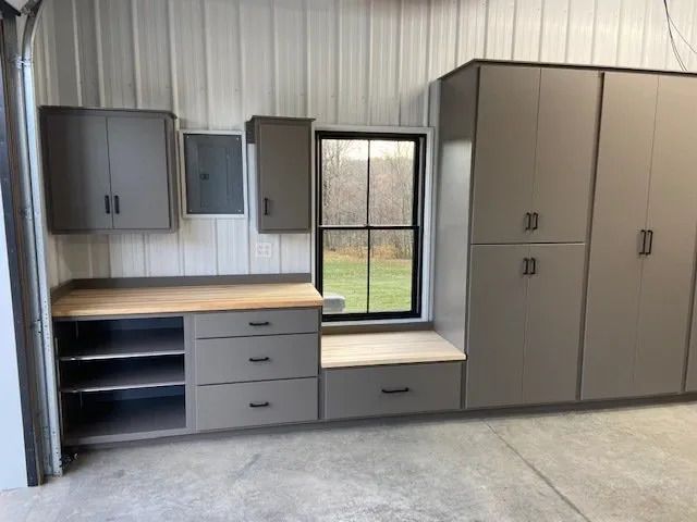 Gray garage cabinets with a wood countertop, drawers, and window.