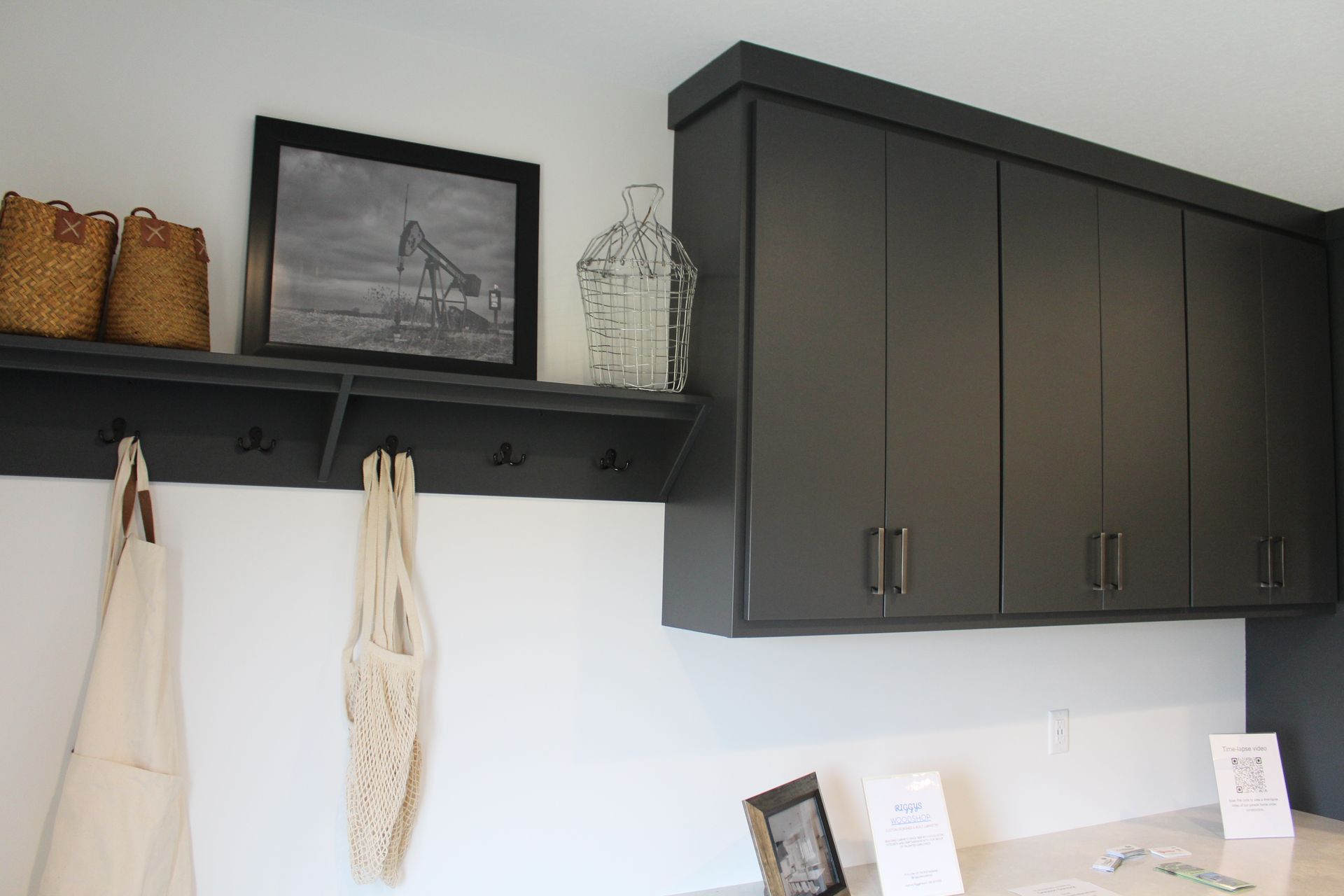 Dark cabinets and shelf with decor over a white counter and wall.