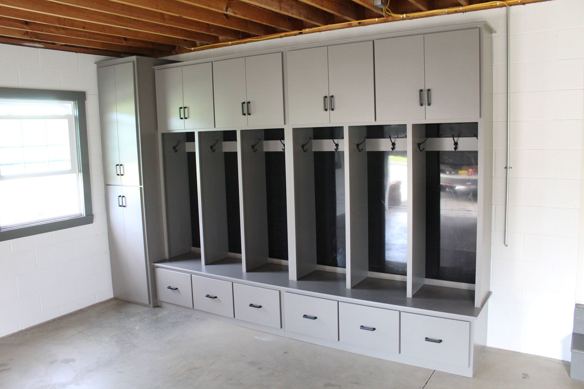 Gray storage cabinets in a garage with open lockers, drawers, and overhead cabinets.