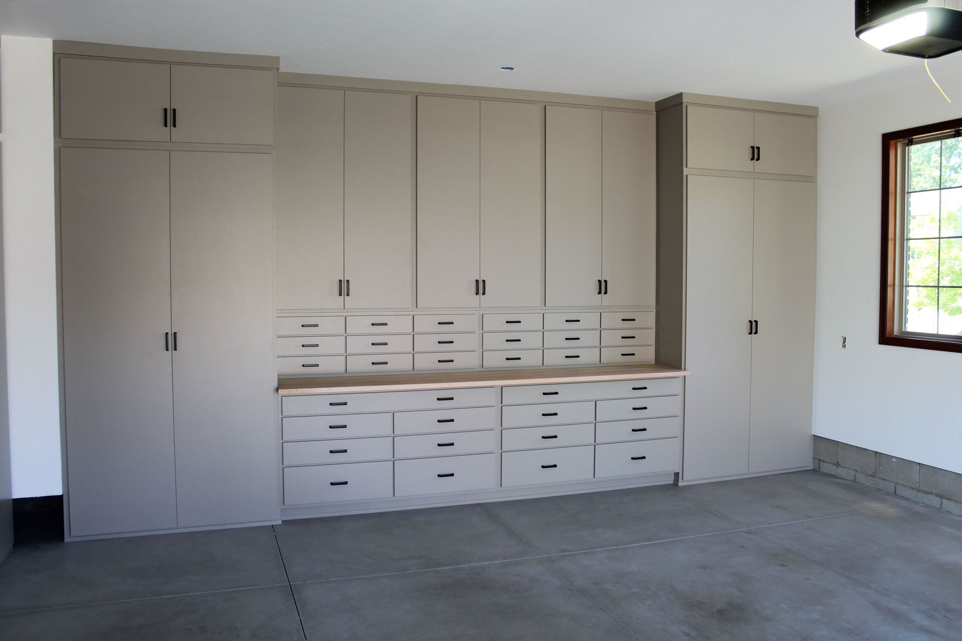 Garage with gray cabinets and drawers along the wall. Light colored countertop.