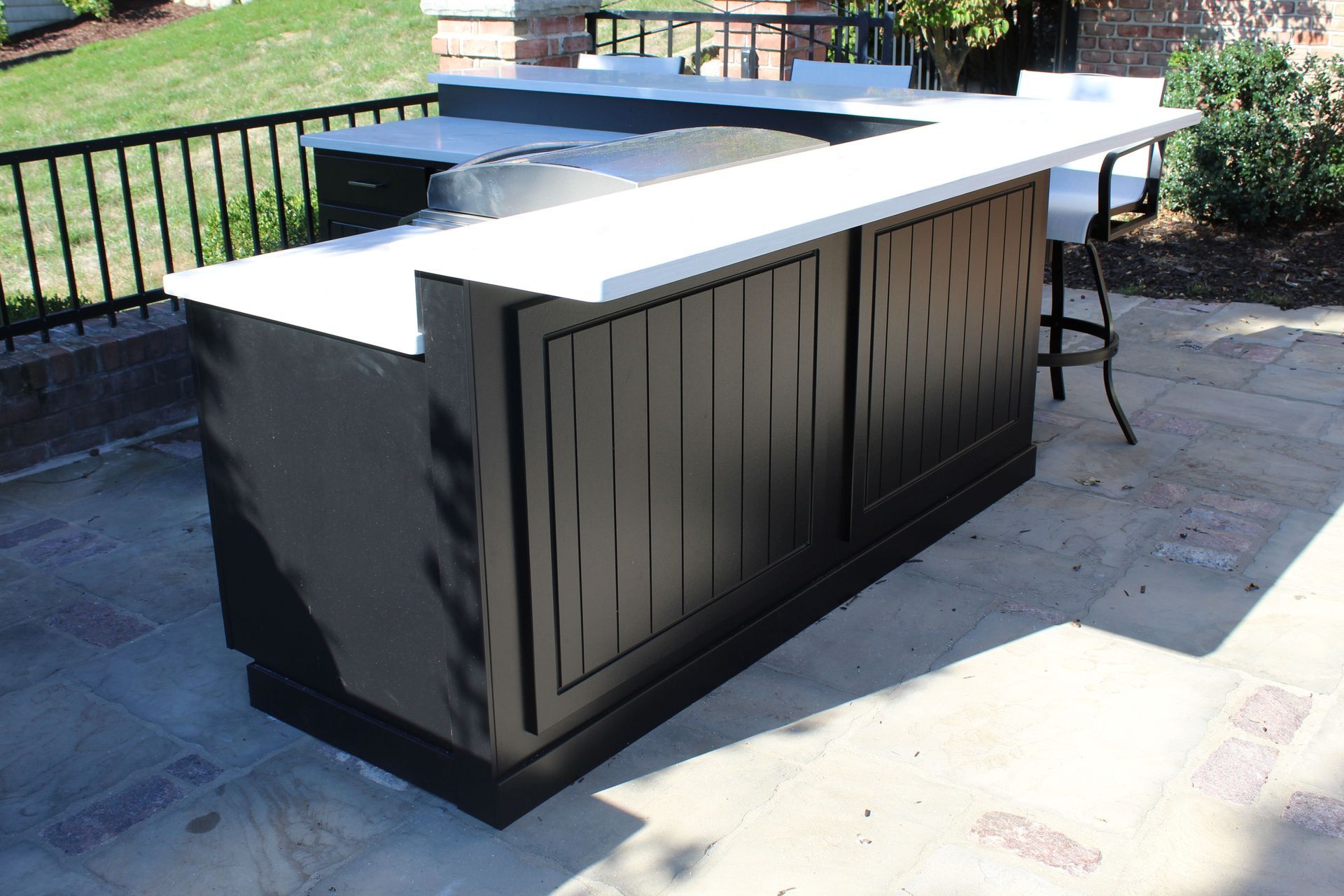 Outdoor black bar with white countertop. A barstool sits at the corner.