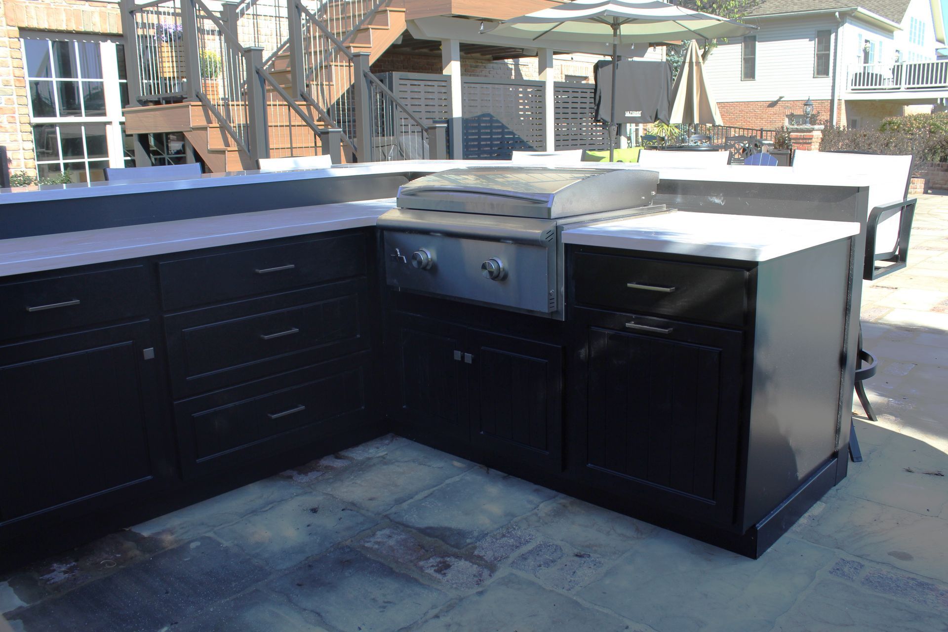 Outdoor black kitchen with built-in grill and countertop on a patio.