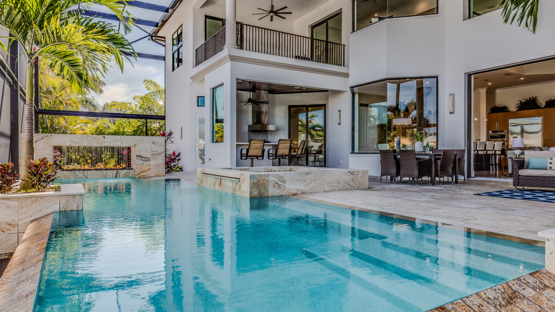 Modern luxury villa with a turquoise swimming pool, patio seating, and open indoor-outdoor living area