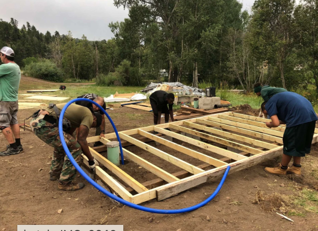 A group of men are working on a wooden structure.