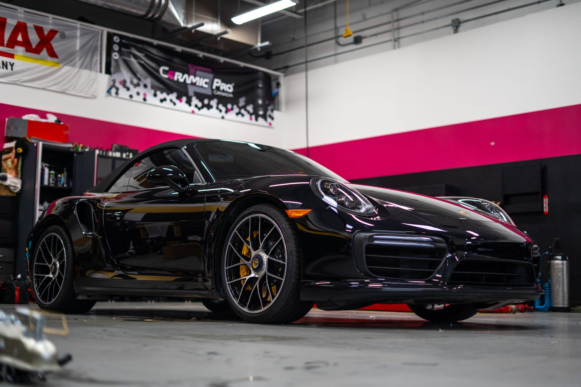 Black Porsche sports car in a garage with pink and black accents.