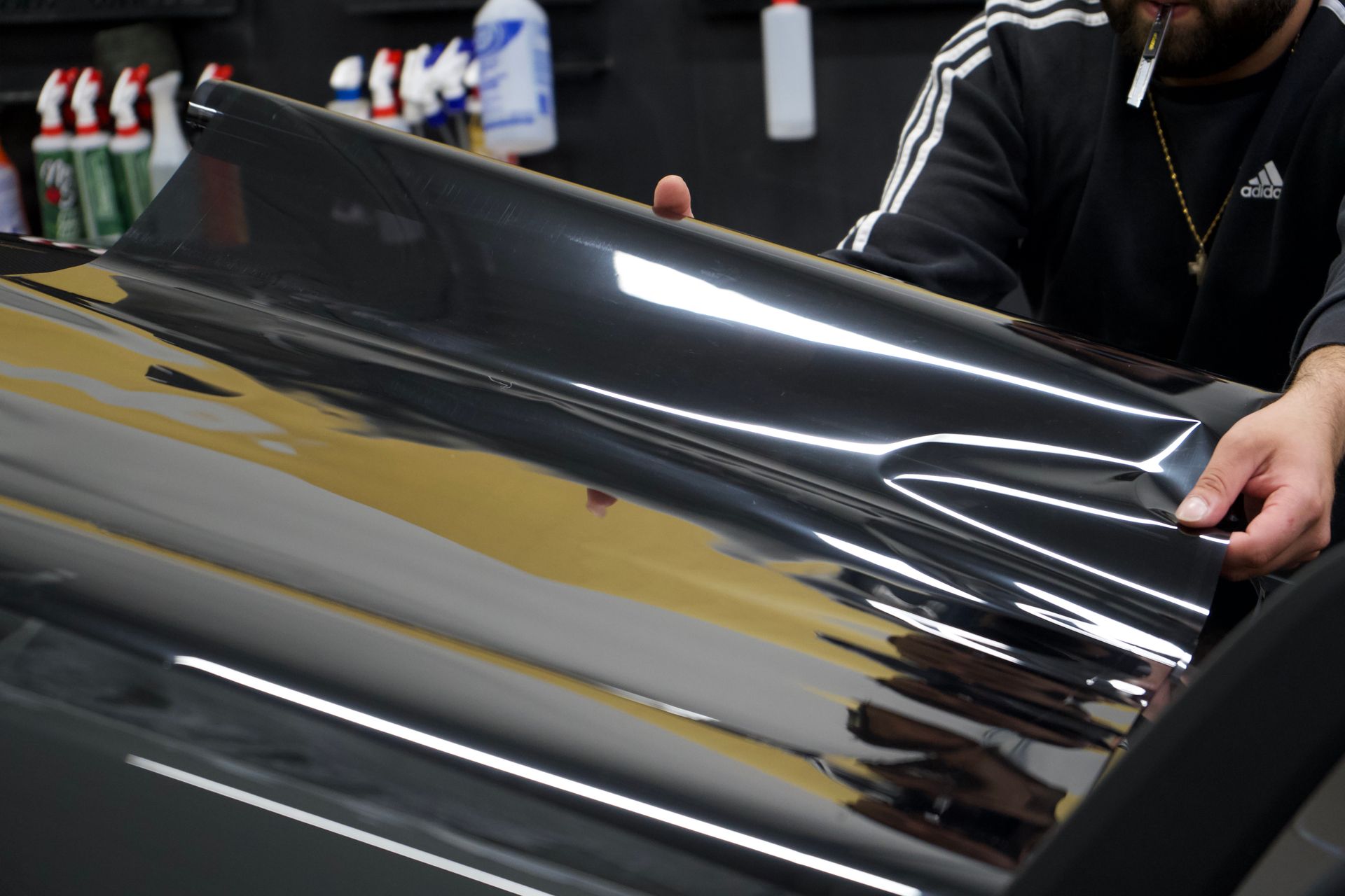 Person holding a dark tinted film sheet, possibly for car window tinting.