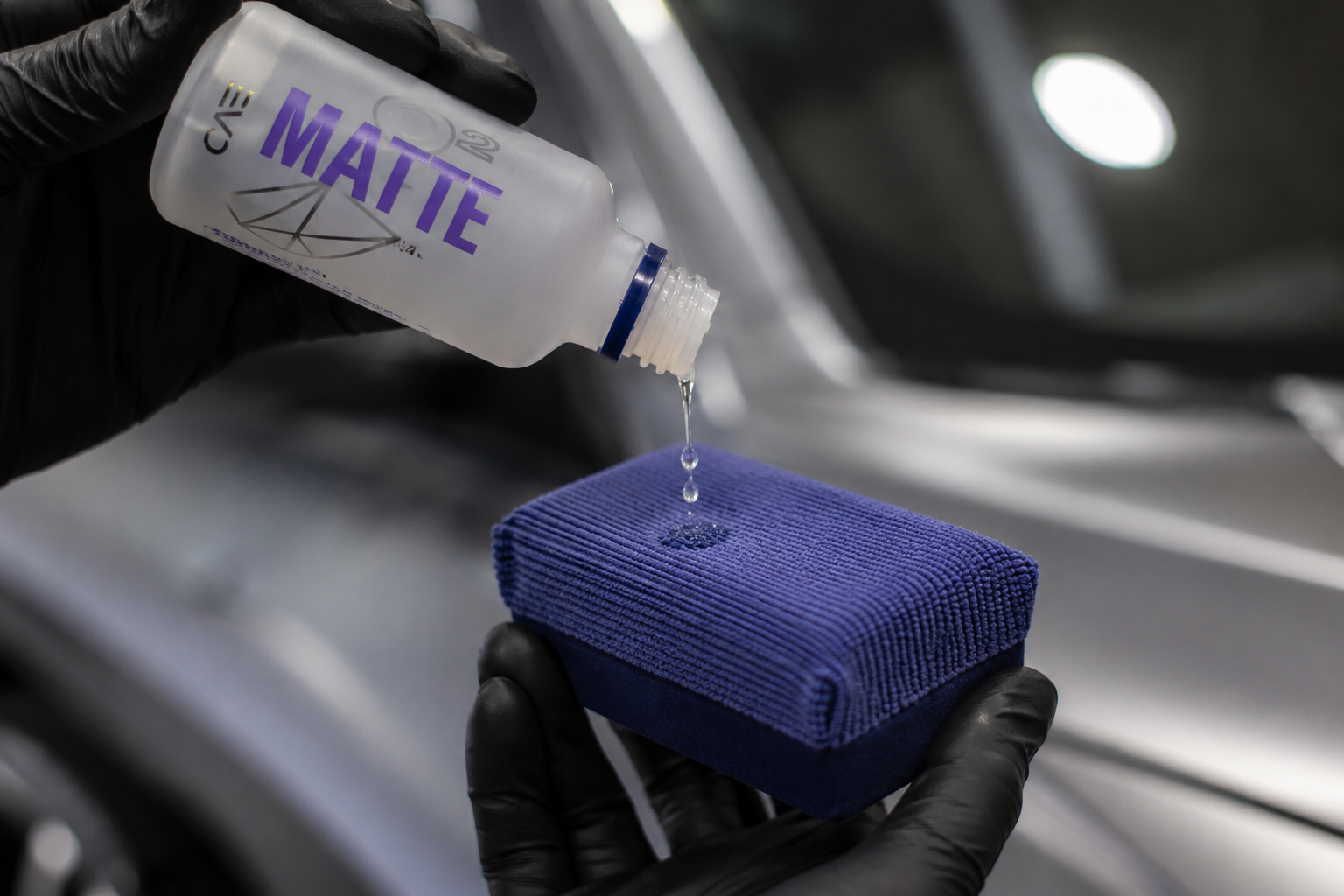 Gloved hands pour liquid from a bottle labeled “MATÉ” onto a blue sponge block.