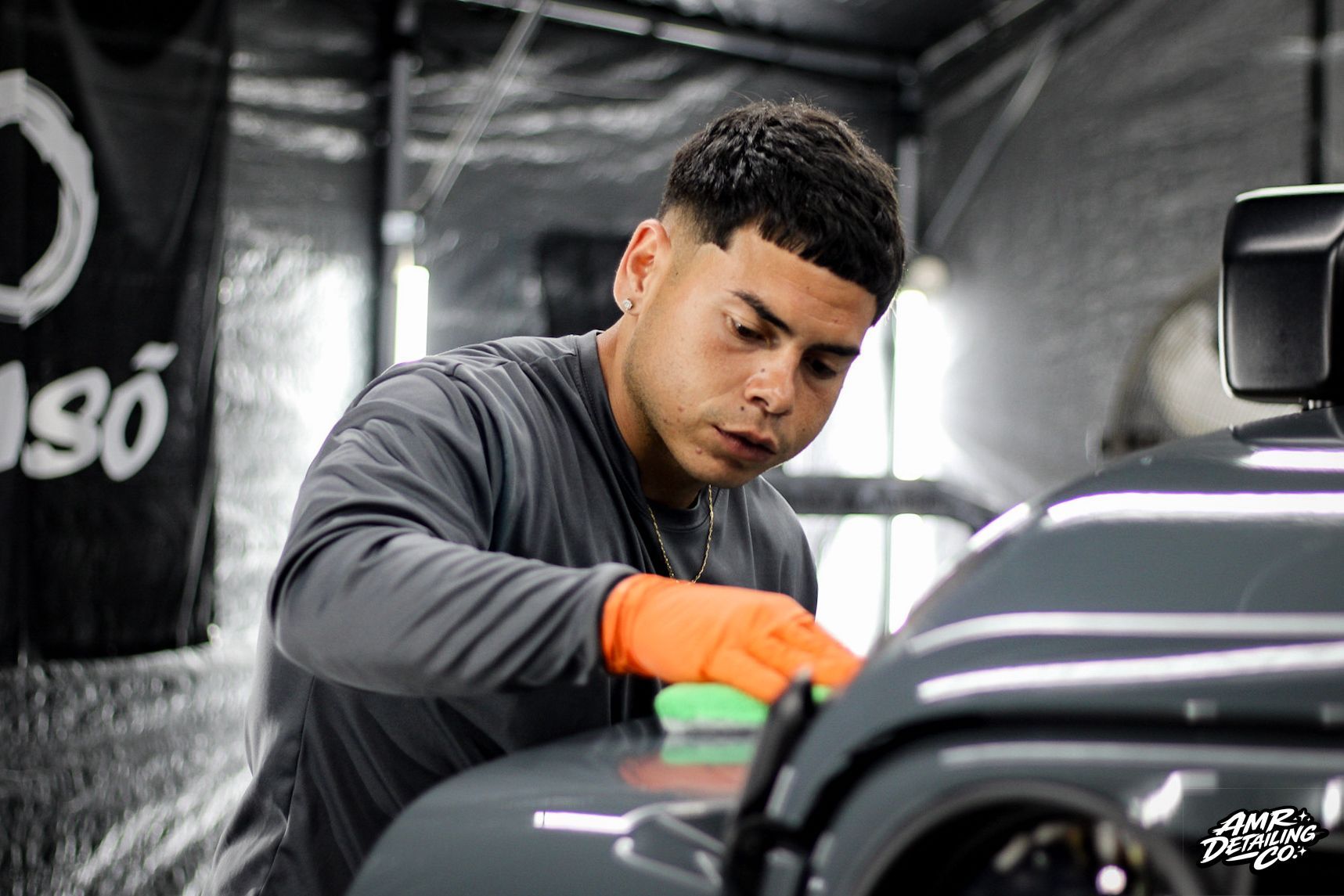 Gloved hand polishing a blue and black car surface with a cloth