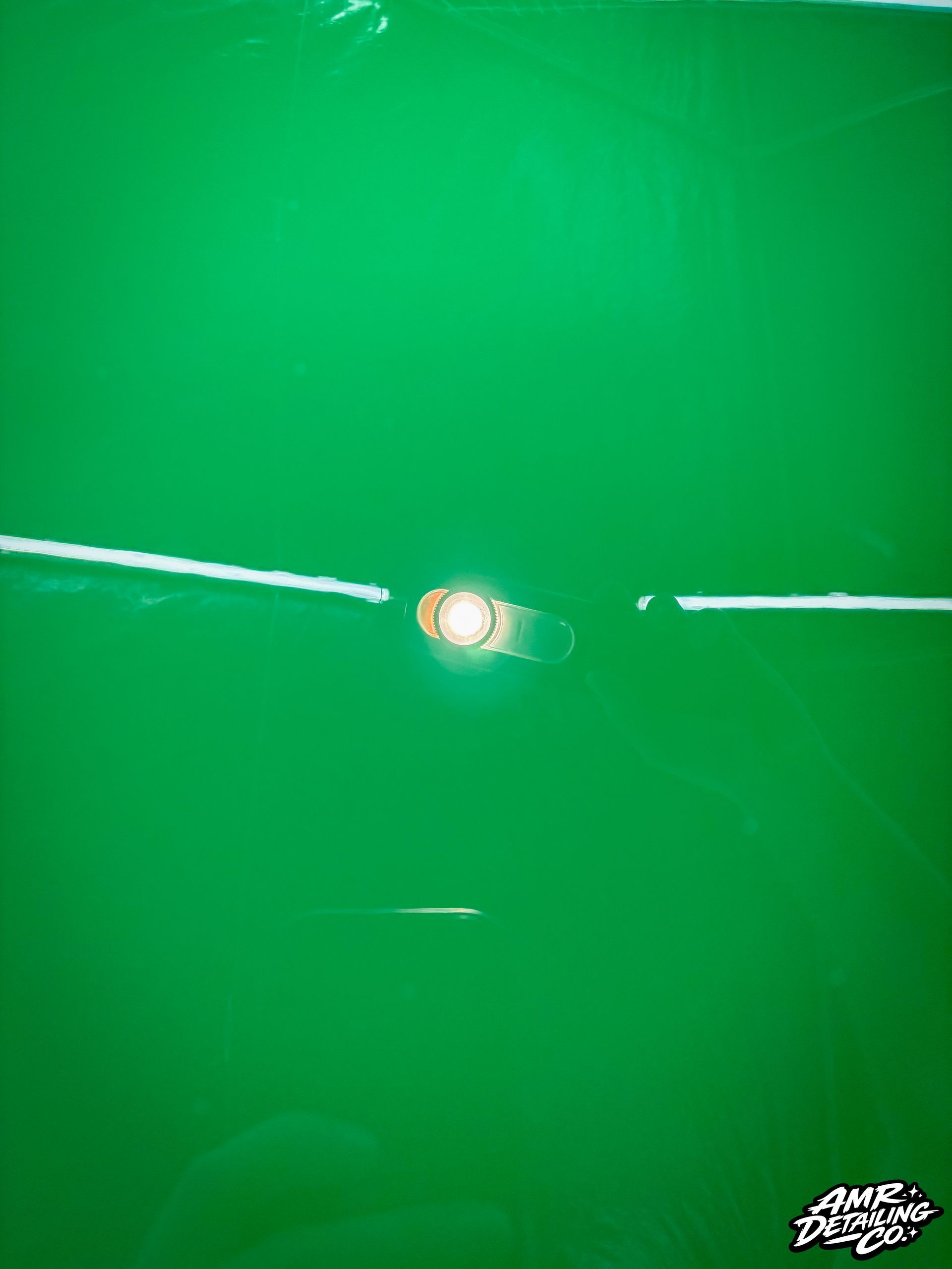 Green surface with a bright light reflection at center and thin white lines across it.