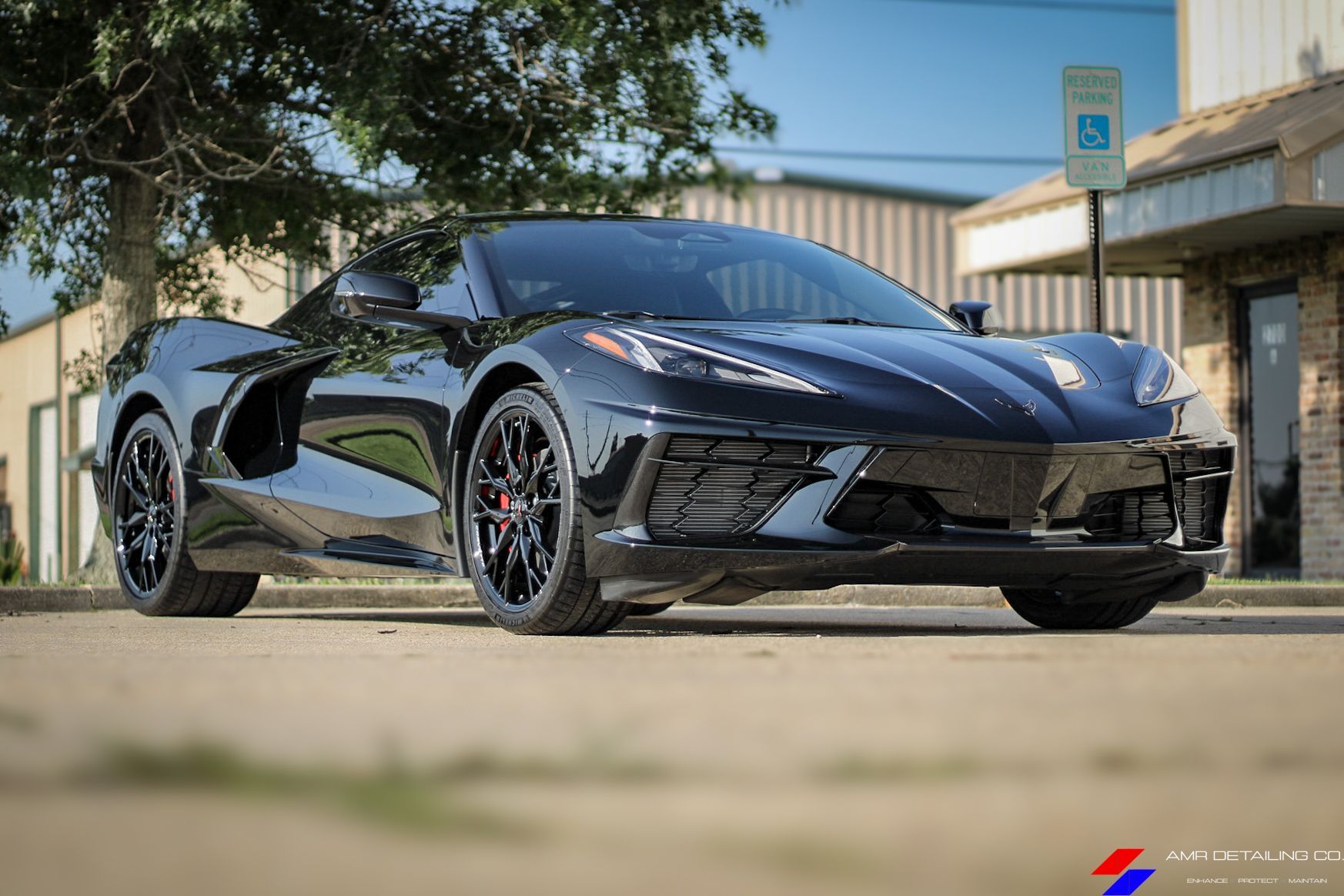 Black sports car parked on a sunny street beside a building