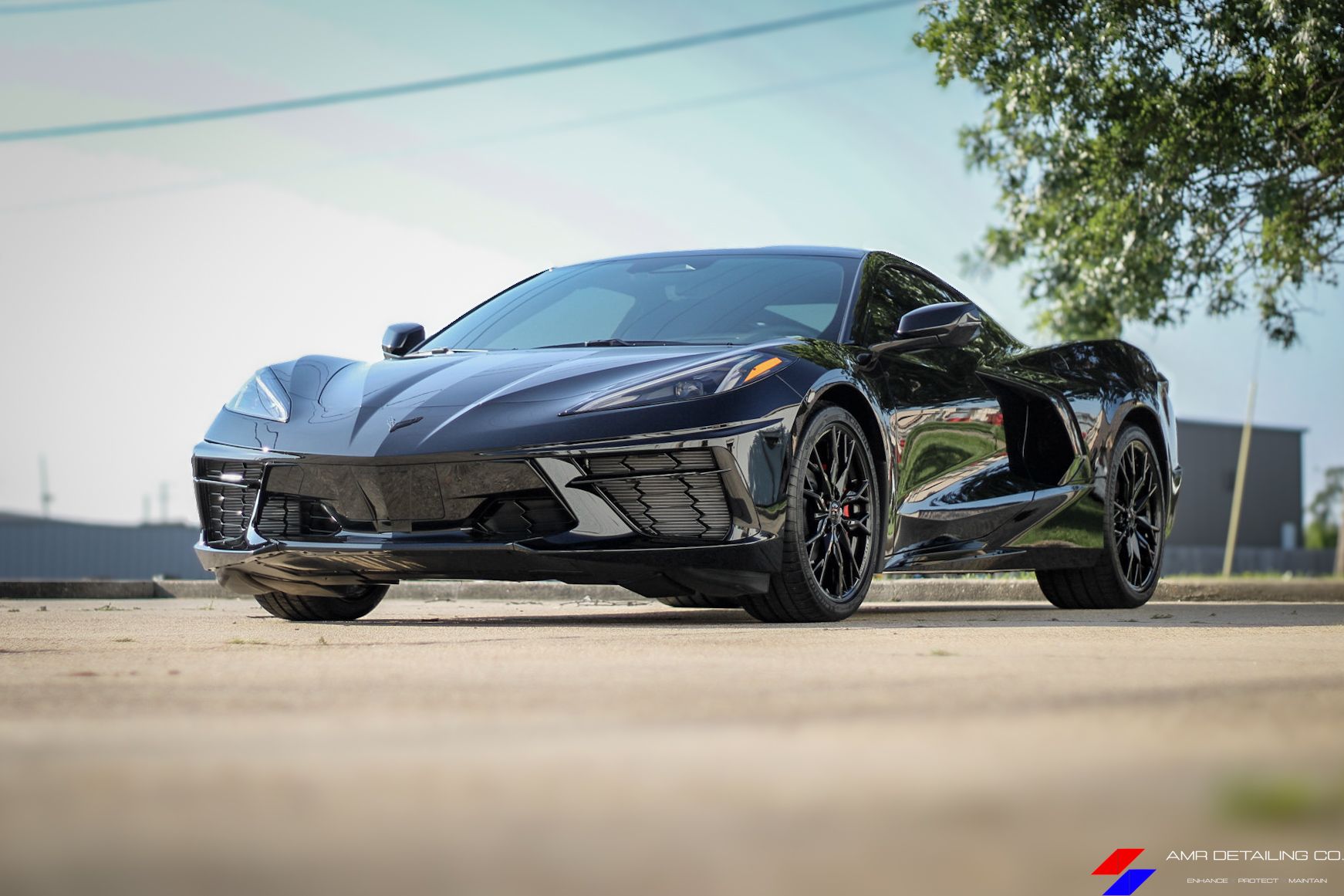 Black sports car parked outdoors on a sunny day, seen from a low angle.