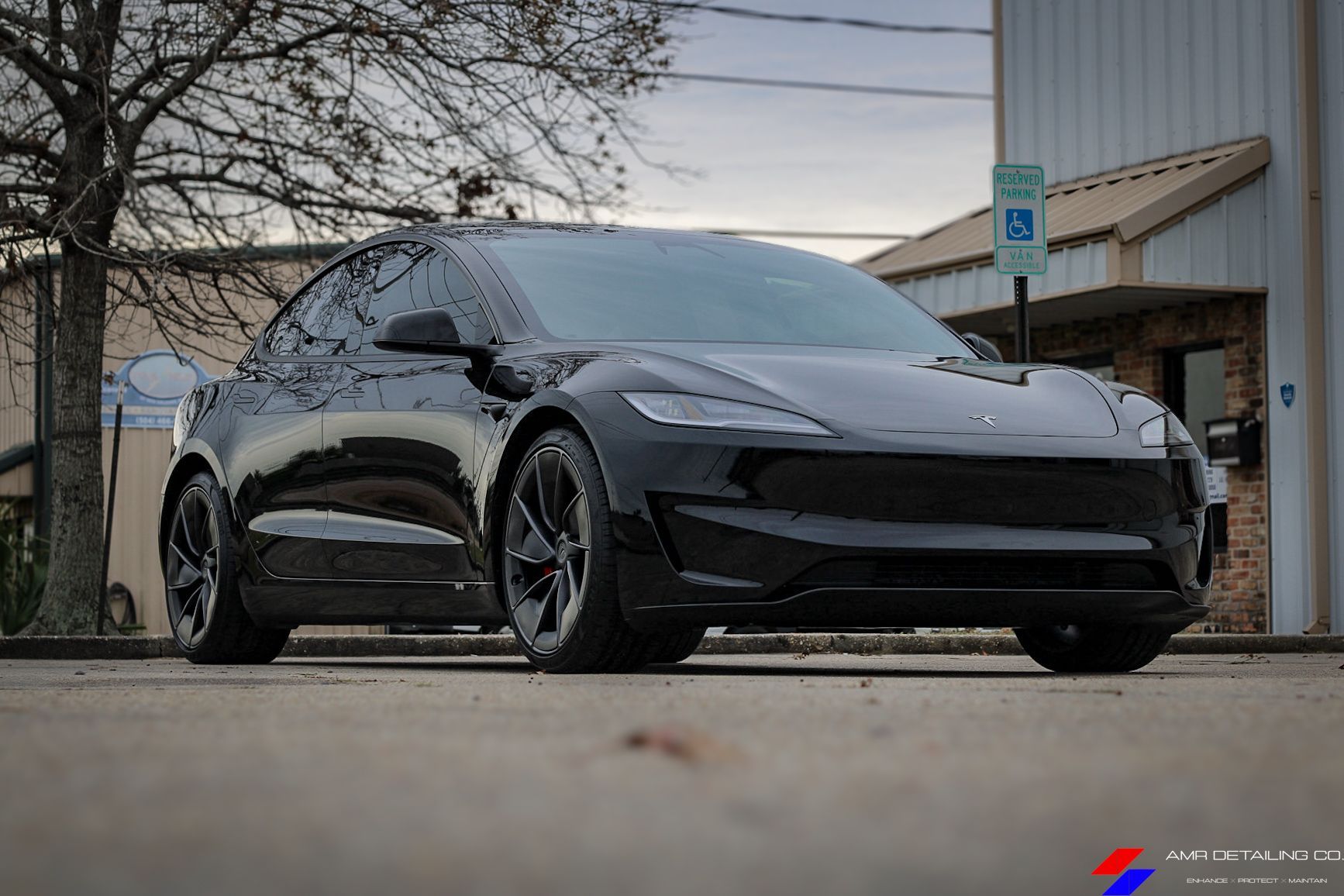 Black sports car parked outside a building on an overcast day