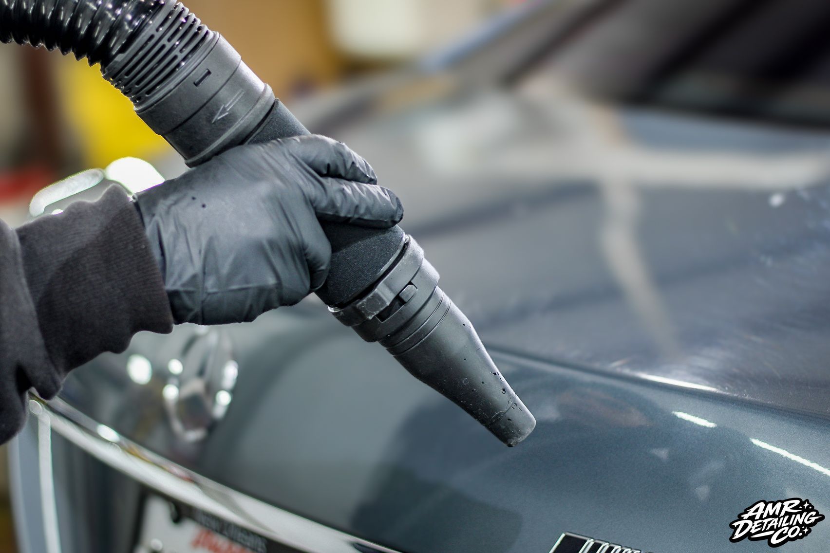 Gloved hand using a steam nozzle to clean a car windshield