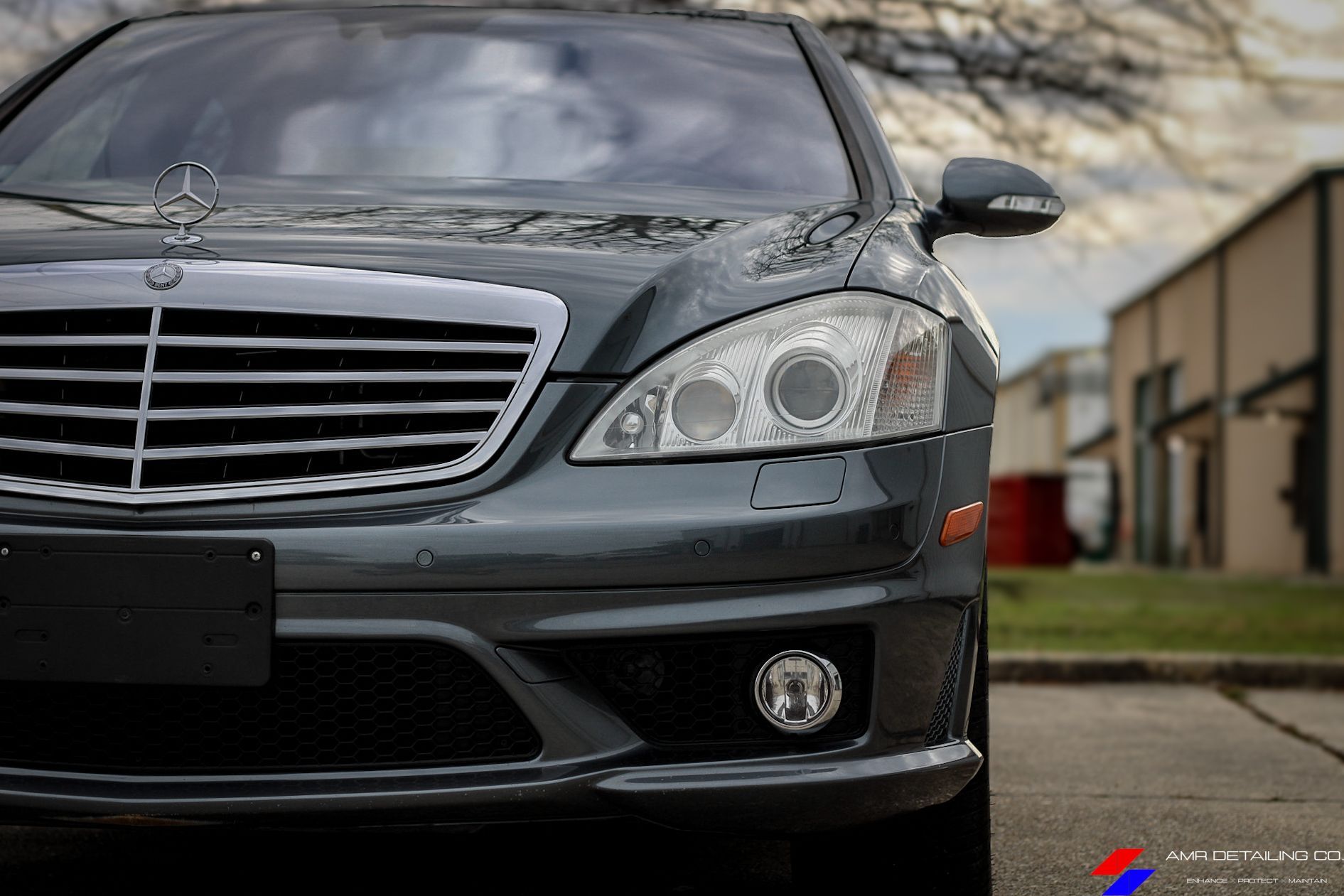Front view of a black Mercedes-Benz sedan parked outdoors near a building.
