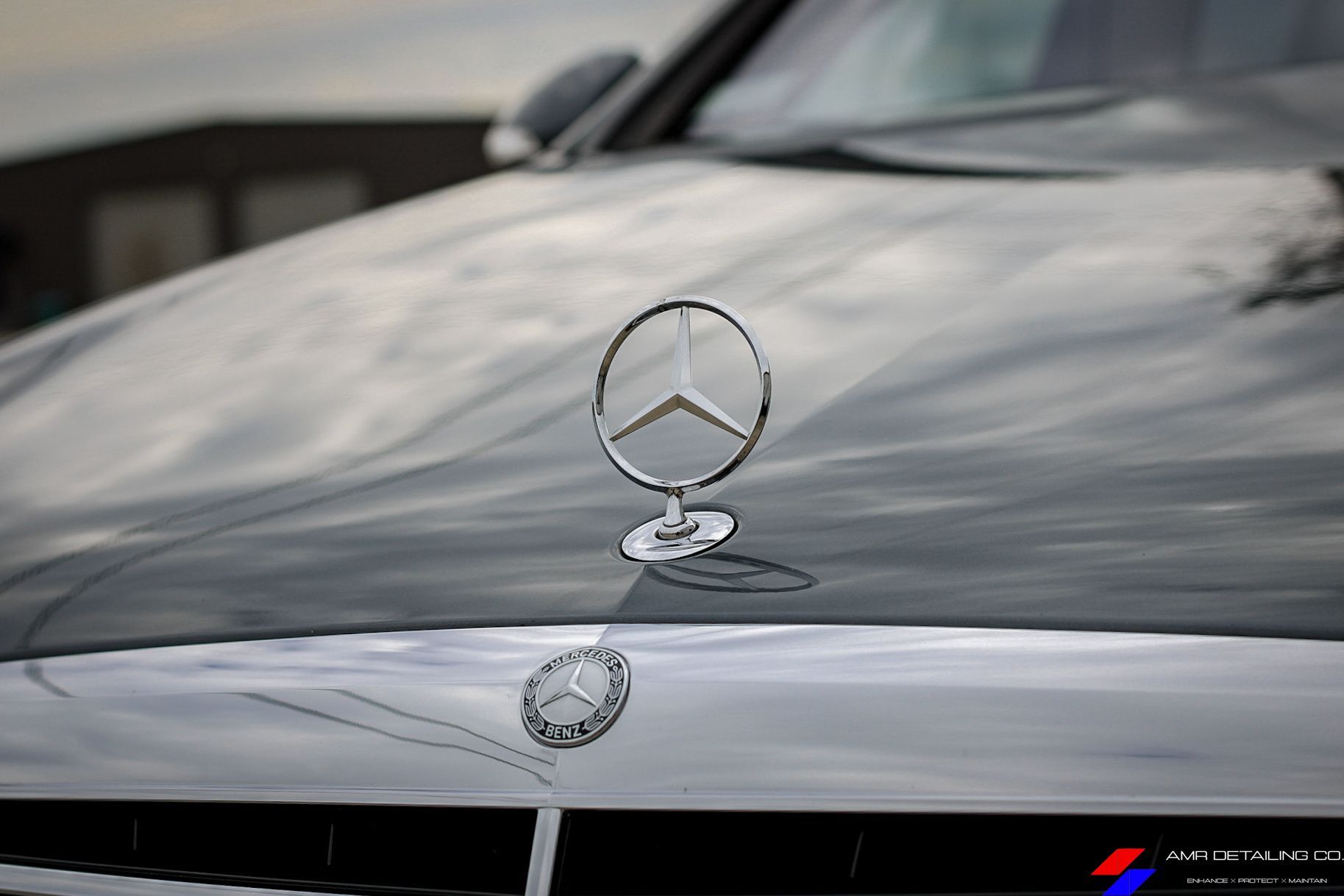 Close-up of a silver Mercedes hood ornament on a glossy car hood