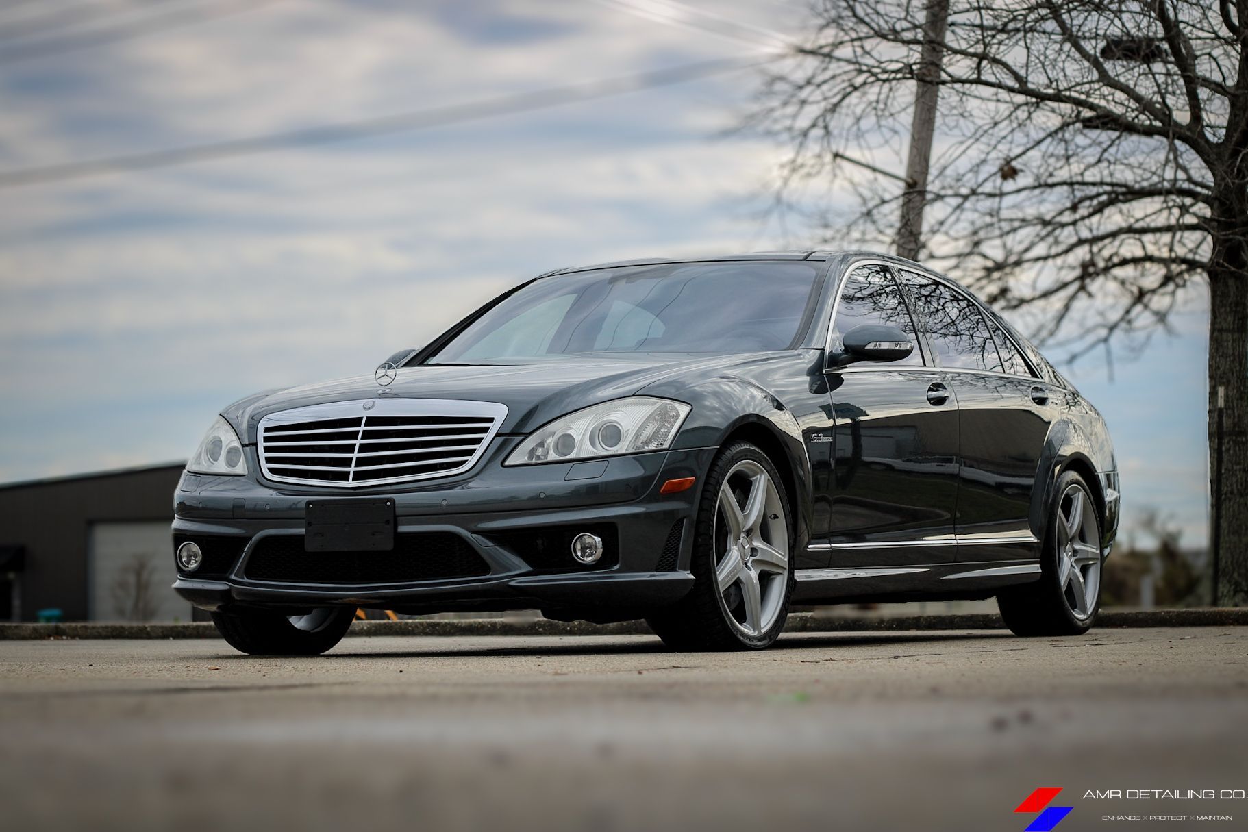 Black sedan parked on a street, front view with chrome grille under cloudy sky.