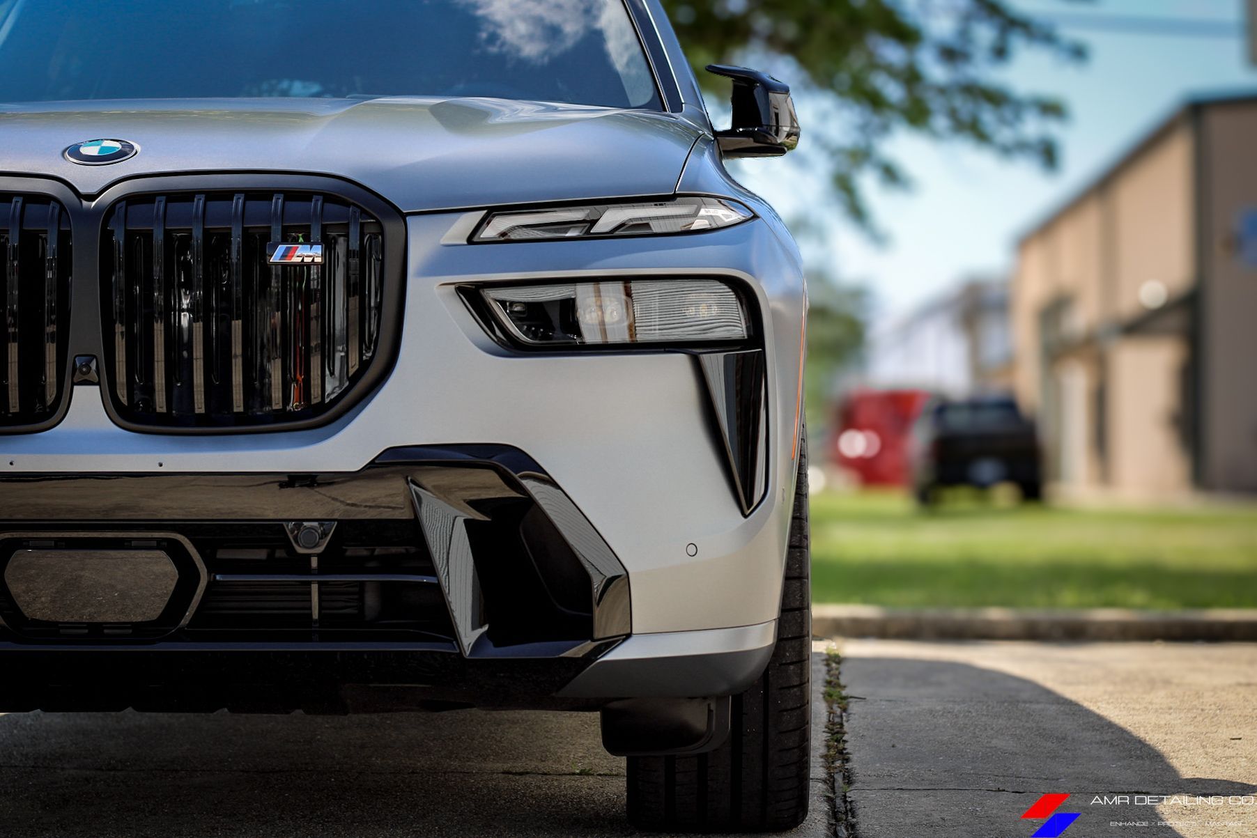 Front view of a white BMW SUV parked on a street, with a blurred building and lawn in the background