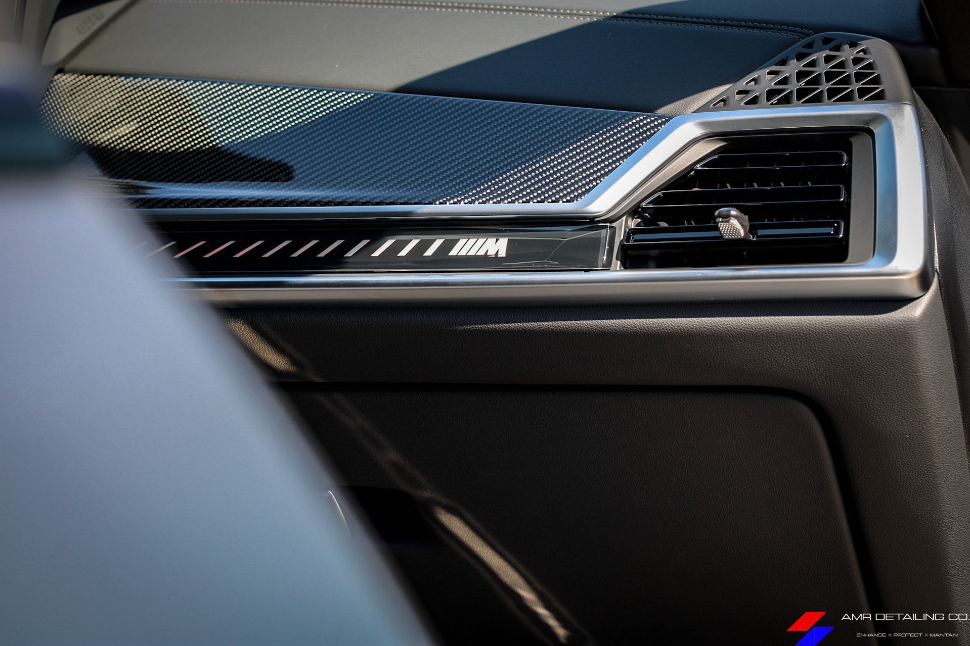 Close-up of a BMW car dashboard air vent and textured interior trim