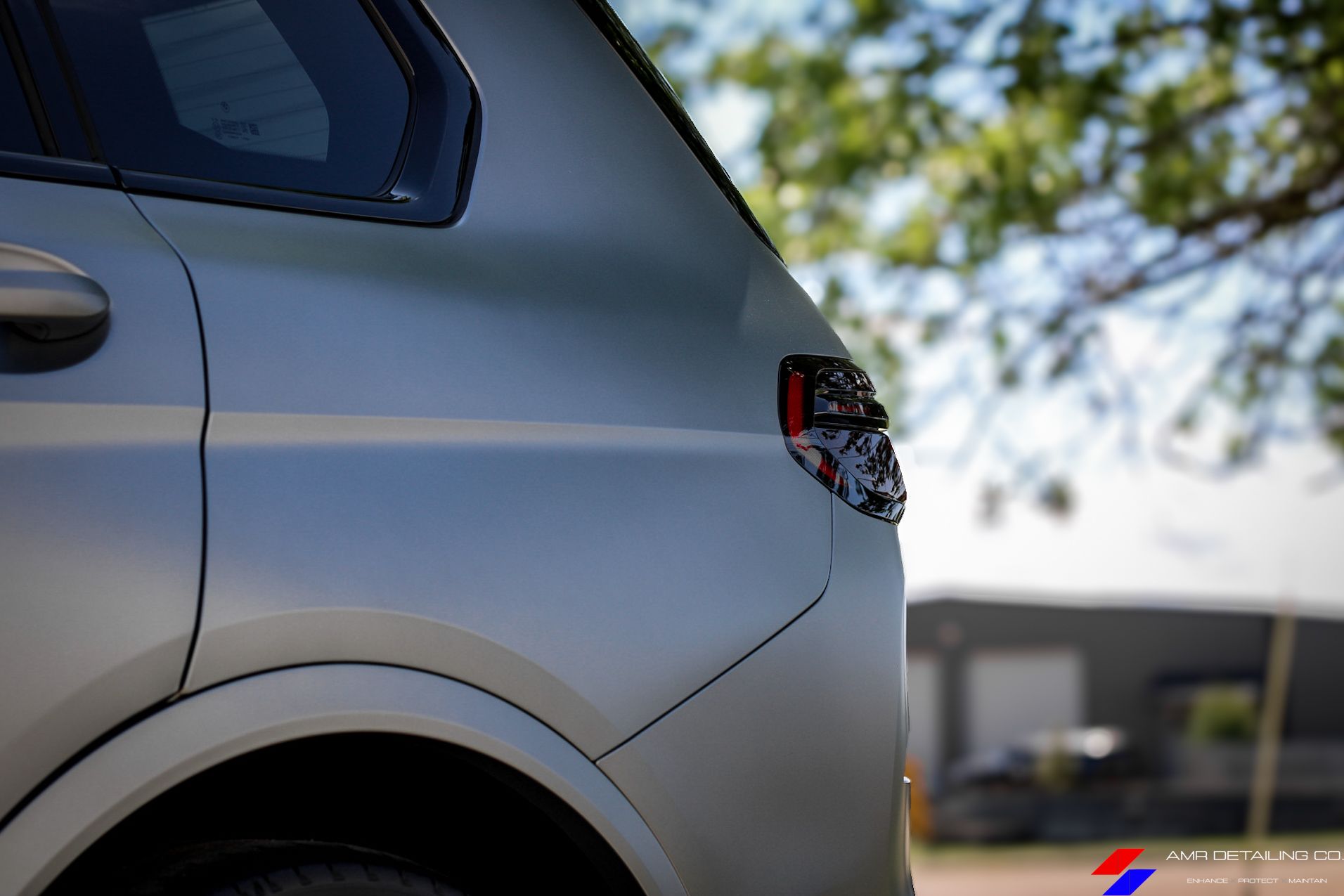 Close-up of a silver SUV parked outdoors, showing the rear side and taillight.