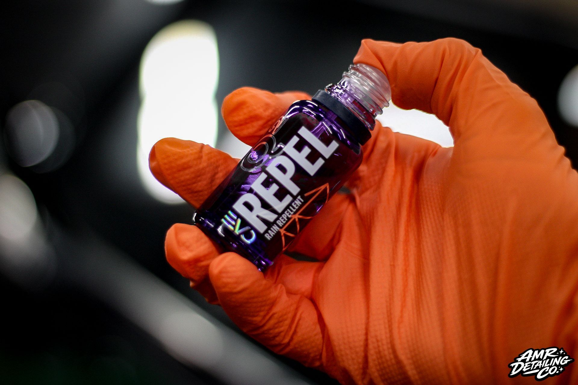 Gloved hand holding a small purple G Fuel Energy bottle against a blurred dark background