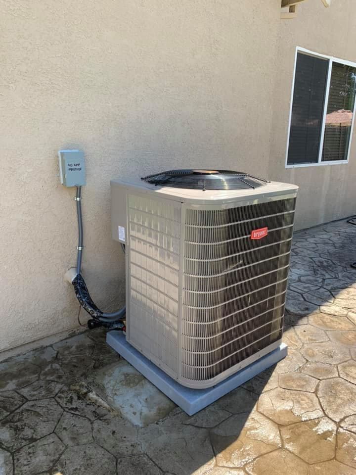 New Bryant air conditioning condenser unit placed beside a tan stucco home.