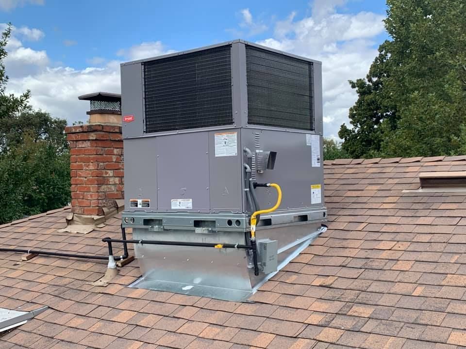 Bryant rooftop unit beside brick chimney vent.
