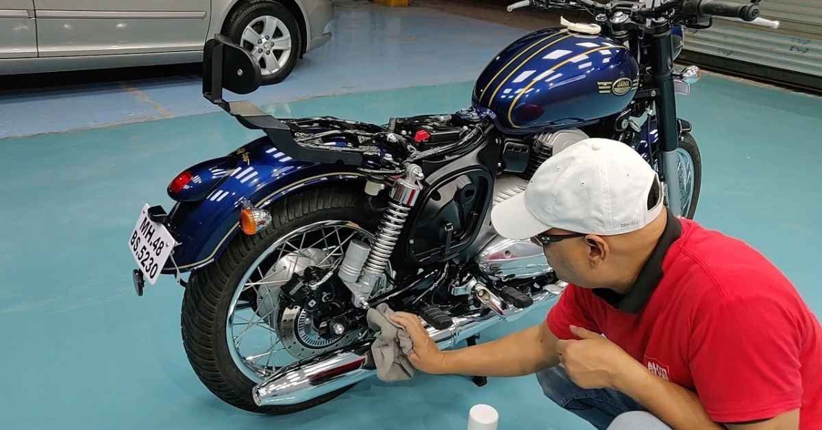 Person in red shirt and white cap working on a blue custom motorcycle in a garage.