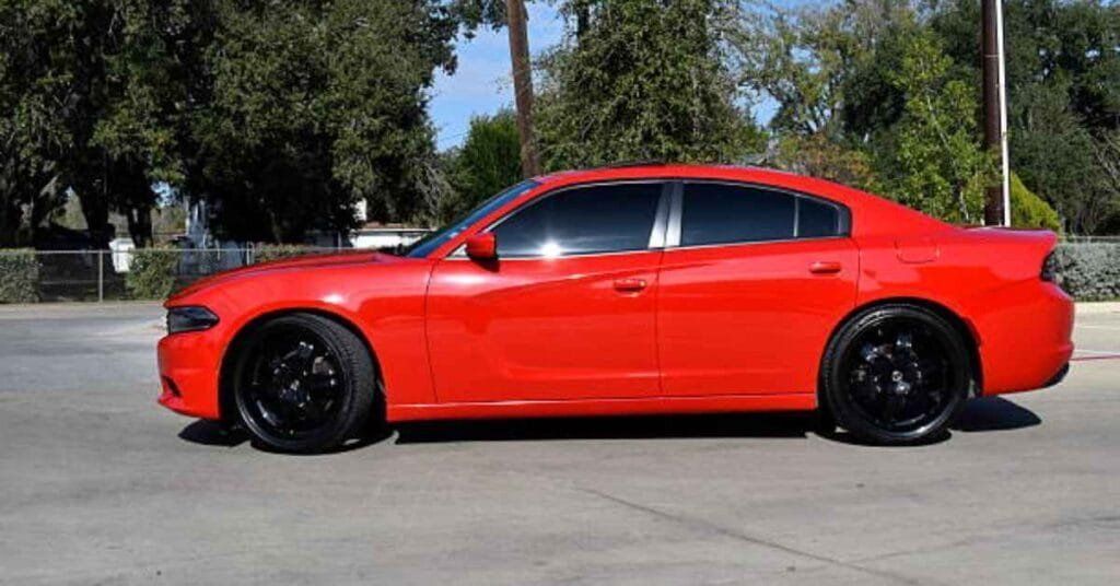 Red sports sedan parked outdoors on a sunny day, with black rims and tinted windows.