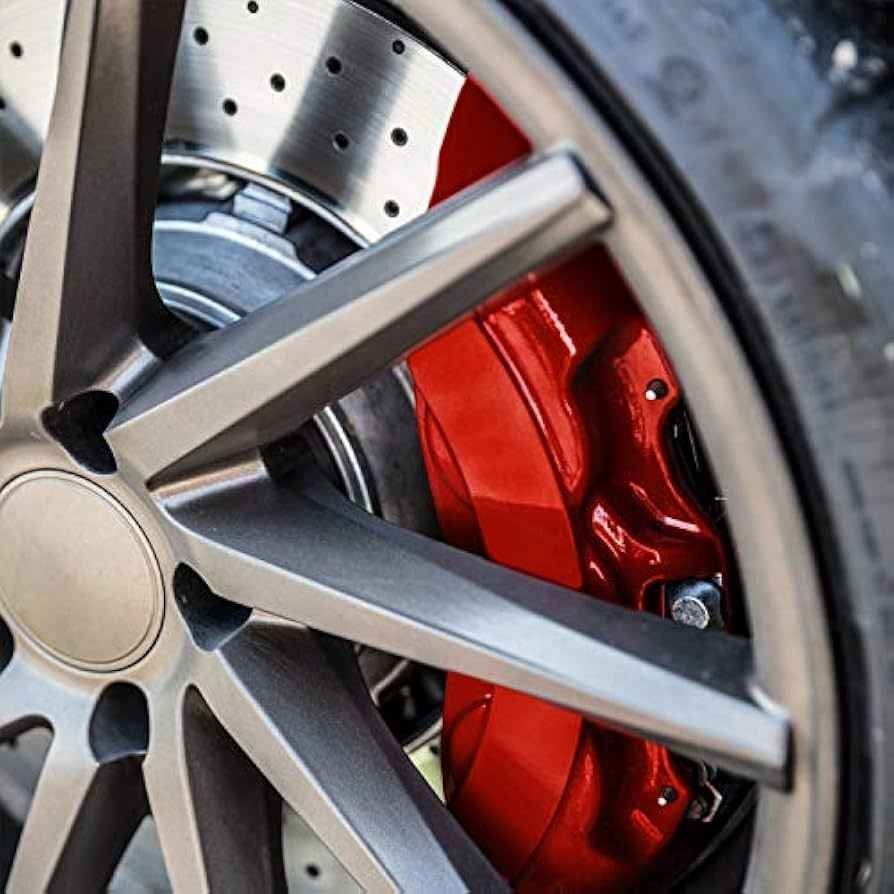 Close-up of a silver car wheel with a red brake caliper and drilled brake rotor