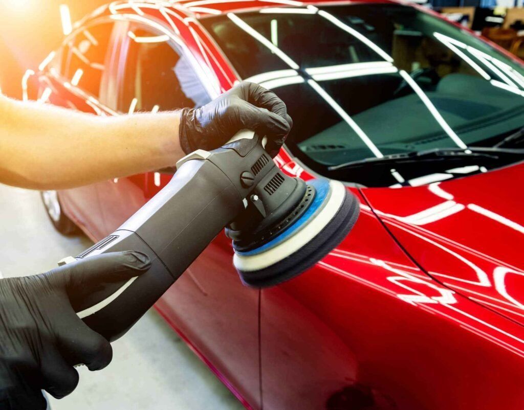 Detailing a red car with a buffer polisher