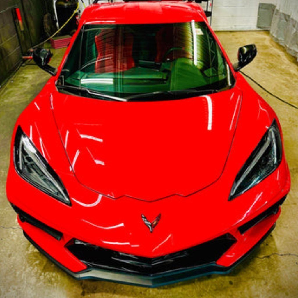 Red sports car in a garage, viewed from the front, with glossy bright red paint.