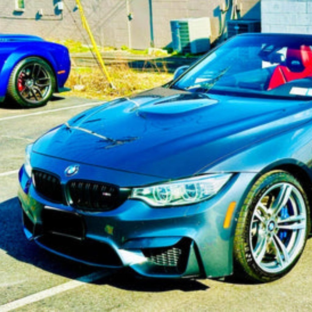Blue BMW sports car parked outdoors in bright sunlight, front angle view