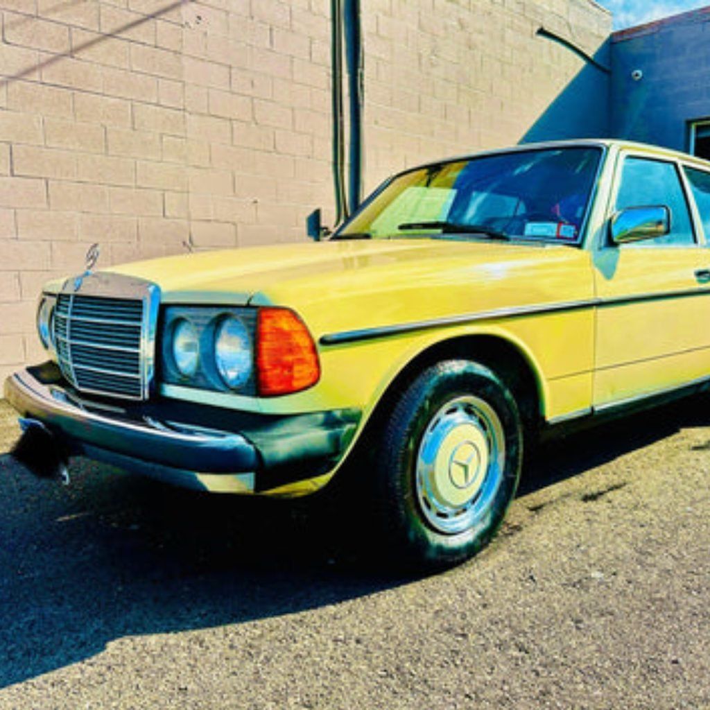 Yellow vintage Mercedes sedan parked by a beige wall in bright sunlight