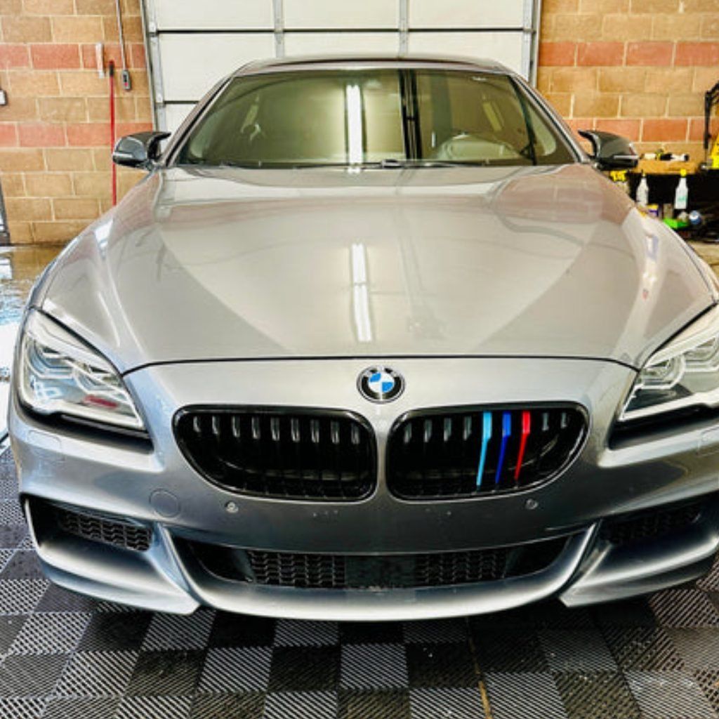 Silver BMW sports car parked indoors in a garage, front view with M-style grille accents.