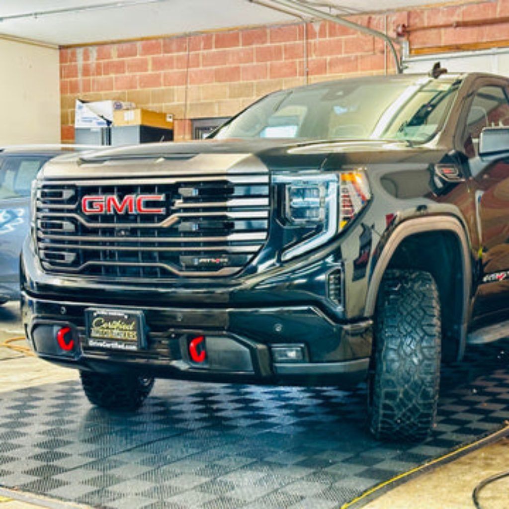 Black GMC pickup truck parked indoors on a checkered floor in a garage or showroom.