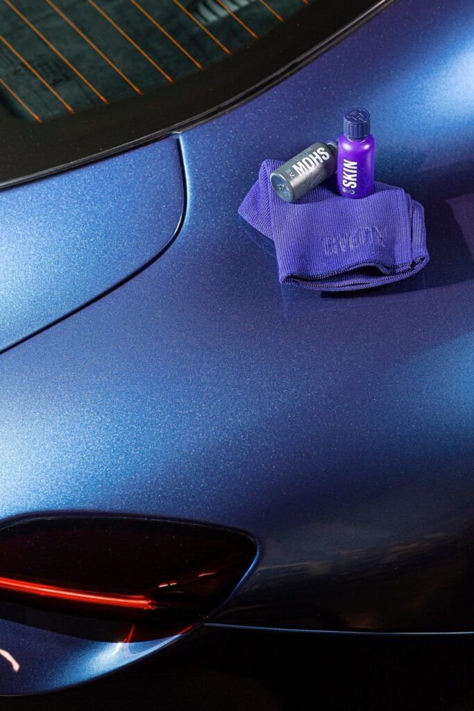 Purple sports car hood with a cloth and two small bottles on top