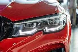 Close-up of a red car’s front headlight and grille