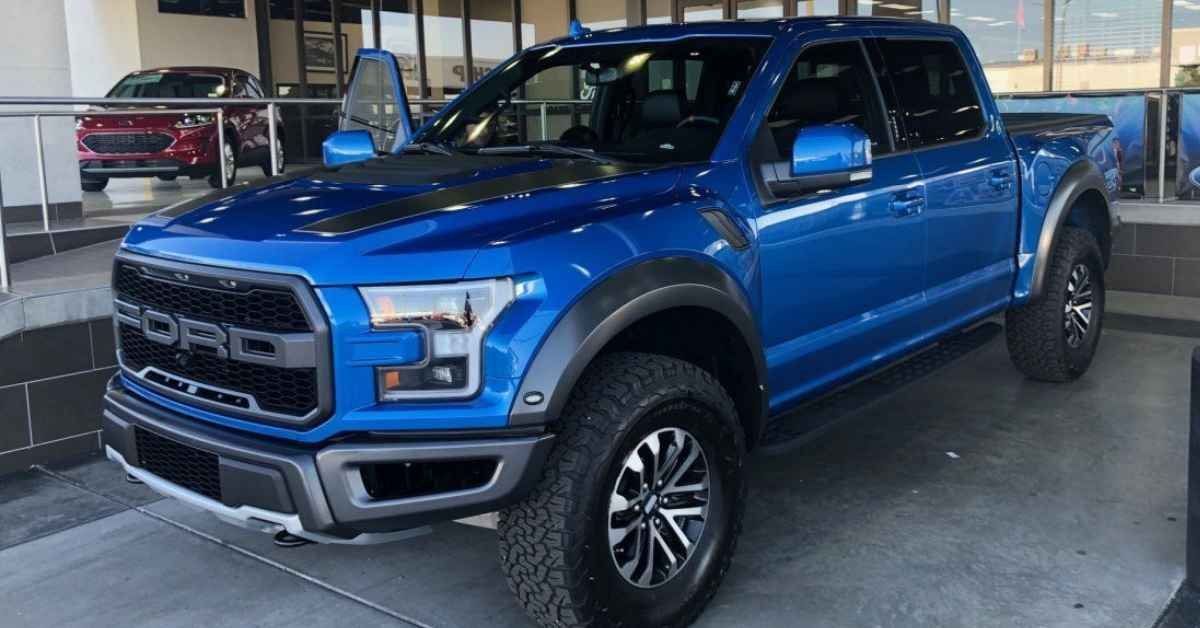 Blue Ford pickup truck parked indoors in a showroom or garage, front three-quarter view